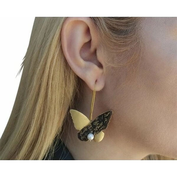 Σκουλαρίκια κρεμαστά μακριά με μαργαριτάρια πεταλούδα - 4667, Κομψά κρεμαστά σκουλαρίκια με μοτίβο πεταλούδας που συνδυάζουν τη χάρη της φύσης με τη σύγχρονη αισθητική. Σχεδιασμένα από την Ελληνίδα Σχεδιάστρια Κοσμημάτων Αικατερίνη Χαλκιαδάκη, αυτά τα μοναδικά χειροποίητα σκουλαρίκια αποτελούν το τέλειο statement κόσμημα για κάθε περίσταση.
Κάθε σκουλαρίκι διαθέτει έναν καλλιτεχνικό συνδυασμό χρυσού και μαύρου ορείχαλκου με εκλεπτυσμένη πατίνα που δημιουργεί μια vintage αίσθηση. Οι φυσικές πέρλες προσδίδουν κλασική κομψότητα, ενώ το μοτίβο της πεταλούδας συμβολίζει τη μεταμόρφωση και την ομορφιά. Τα μακριά, κρεμαστά φτερά κινούνται γραφικά με κάθε κίνηση, προσελκύοντας τα βλέμματα.