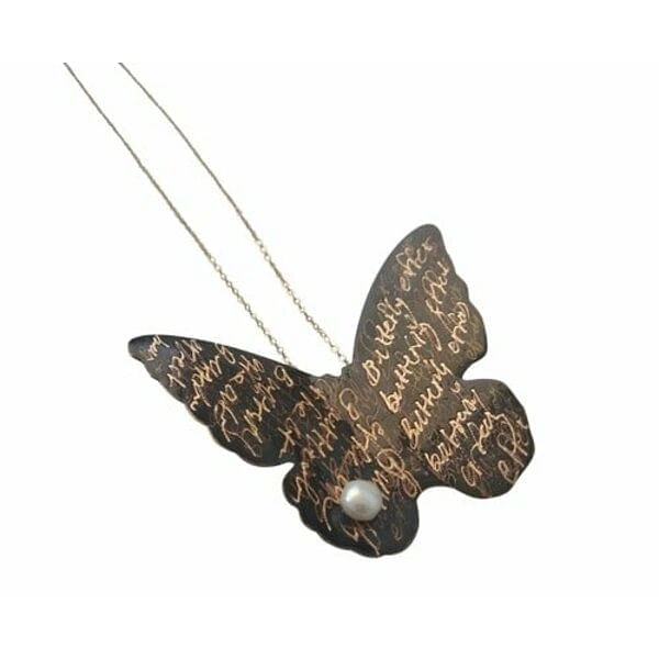 Μεγάλο εντυπωσιακό κολιέ μακρύ μαργαριτάρι πεταλούδα - 4691, Ανακαλύψτε το μεγάλο εντυπωσιακό κολιέ με πεταλούδα και μαργαριτάρι που θα γίνει το signature κόσμημα της γκαρνταρόμπας σας. Αυτό το χειροποίητο statement κολιέ, σχεδιασμένο από την Ελληνίδα Σχεδιάστρια Κοσμημάτων Αικατερίνη Χαλκιαδάκη, συνδυάζει την κομψότητα της πεταλούδας με την κλασική ομορφιά του μαργαριταριού.
Κατασκευασμένο από υψηλής ποιότητας ορείχαλκο με μαύρη πατίνα, το κολιέ διαθέτει ένα εντυπωσιακό μοτίβο πεταλούδας που φέρει χαραγμένα γράμματα, δημιουργώντας ένα μοναδικό καλλιτεχνικό αποτέλεσμα. Το φυσικό μαργαριτάρι προσθέτει μια πινελιά κομψότητας και φωτεινότητας στον σχεδιασμό. Το μακρύ μήκος του κολιέ το καθιστά ιδανικό για layering ή για να φορεθεί μόνο του ως statement κόσμημα.
