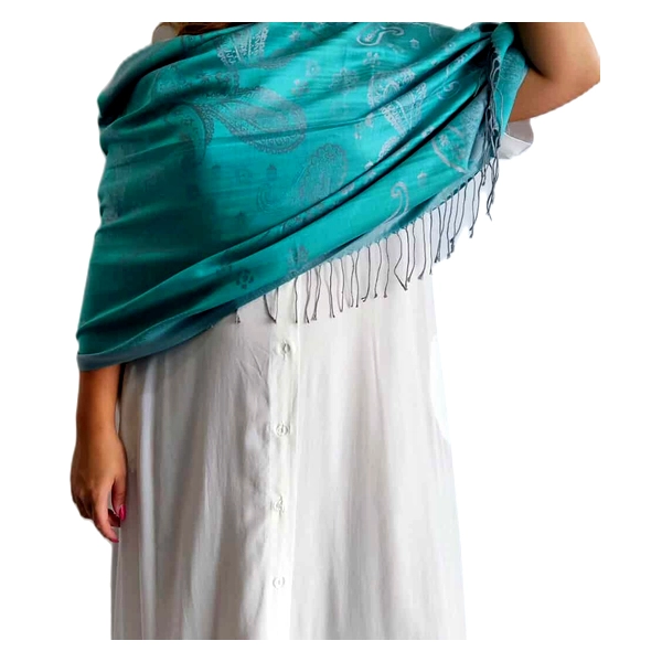 Αυτή η πολυτελής εσάρπα σε υπέροχο τιρκουάζ χρώμα αποτελεί ένα εξαιρετικό αξεσουάρ για κάθε γυναικεία γκαρνταρόμπα. Κατασκευασμένη από εκλεκτό συνδυασμό 90% κασμίρ και 10% μετάξι, προσφέρει απαράμιλλη απαλότητα και ζεστασιά με μια λεπτή, μεταξένια αίσθηση. Το εντυπωσιακό διακοσμητικό μοτίβο με λεπτές αποχρώσεις και διακριτικά σχέδια στην επιφάνειά της προσδίδει κομψότητα, ενώ οι λεπτοί κρόσσοι στις άκρες ολοκληρώνουν το φινετσάτο σχέδιο. Η εσάρπα μπορεί να φορεθεί με πολλούς τρόπους \u002D ριχτή στους ώμους για μια επίσημη βραδινή εμφάνιση, τυλιγμένη γύρω από το λαιμό για καθημερινή κομψότητα ή ακόμα και σαν σάρι πάνω από ένα απλό λευκό φόρεμα όπως φαίνεται στην εικόνα. Συνδυάζεται άψογα με λευκά, μπεζ και μαύρα ρούχα, ενώ είναι ιδανική για επίσημες εκδηλώσεις, κοκτέιλ πάρτι ή ακόμα και για να προσθέσει χρώμα σε ένα επαγγελματικό σύνολο. Η πολυτελής υφή και το ζωντανό τιρκουάζ χρώμα της την καθιστούν ένα διαχρονικό κομμάτι που θα απολαμβάνετε για χρόνια.