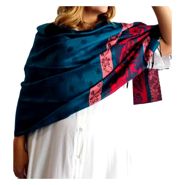 Αυτή η εκλεπτυσμένη εσάρπα από 90% κασμίρ και 10% μετάξι αποτελεί ένα αριστούργημα πολυτελούς αισθητικής. Το κυρίαρχο βαθύ πετρόλ χρώμα της δημιουργεί μια εντυπωσιακή αντίθεση με τις ζωηρές κόκκινες και ροζ λεπτομέρειες στις άκρες. Διακοσμημένη με διακριτικά λουλουδάτα μοτίβα, η εσάρπα συνδυάζει κομψότητα και θηλυκότητα. Η απαλή υφή του κασμίρ προσφέρει εξαιρετική ζεστασιά και άνεση, ενώ το μετάξι προσδίδει μια λεπτή γυαλάδα που αναβαθμίζει την εμφάνισή της. Ιδανική για βραδινές εξόδους, επίσημες εκδηλώσεις ή ακόμα και για καθημερινή κομψότητα, αυτή η εσάρπα μπορεί να φορεθεί με απλά μονόχρωμα φορέματα όπως το λευκό της φωτογραφίας, αλλά και με επίσημα σύνολα ή casual ρούχα. Η ευέλικτη φύση της επιτρέπει πολλαπλούς τρόπους στυλιζαρίσματος \u002D ως παραδοσιακό σάλι, ως φουλάρι ή ακόμα και ως διακοσμητικό στοιχείο σε μια τσάντα. Οι κρόσσια στις άκρες της προσθέτουν μια νότα διαχρονικής κομψότητας, ολοκληρώνοντας αυτό το μοναδικό αξεσουάρ που συνδυάζει πολυτέλεια και λειτουργικότητα