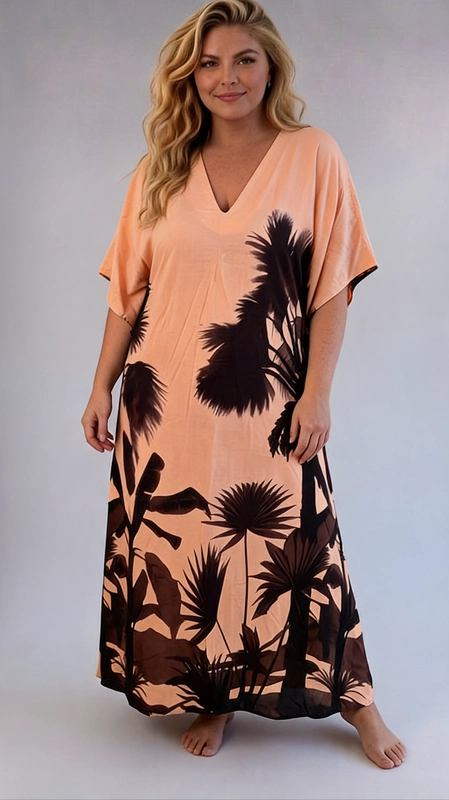Ένα εντυπωσιακό maxi φόρεμα τύπου kaftan που συνδυάζει το ροδακινί χρώμα με σκούρες καφέ\u002Dμαύρες σιλουέτες τροπικής βλάστησης, δημιουργώντας ένα αποτέλεσμα που παραπέμπει σε εξωτικά τοπία. Το μοτίβο αποτελείται από φοίνικες, τροπικά φύλλα και βλάστηση που καλύπτουν το κάτω μέρος και τα πλαϊνά του φορέματος, αφήνοντας το πάνω τμήμα πιο καθαρό και φωτεινό. Το φόρεμα διαθέτει λαιμόκοψη σε σχήμα V, φαρδιά κοντά μανίκια τύπου batwing και ελεύθερη, ρέουσα γραμμή που χαρίζει άνεση και κομψότητα. Η κοπή του είναι ιδιαίτερα κολακευτική για plus size σιλουέτες, καθώς αναδεικνύει τις καμπύλες χωρίς να σφίγγει. Ιδανικό για καλοκαιρινές διακοπές, βόλτες στην παραλία ή ως beach cover\u002Dup, αλλά και για χαλαρές καλοκαιρινές βραδιές. Μπορεί να συνδυαστεί με σανδάλια και ψάθινη τσάντα για ένα ολοκληρωμένο summer look που δεν περνά απαρατήρητο.