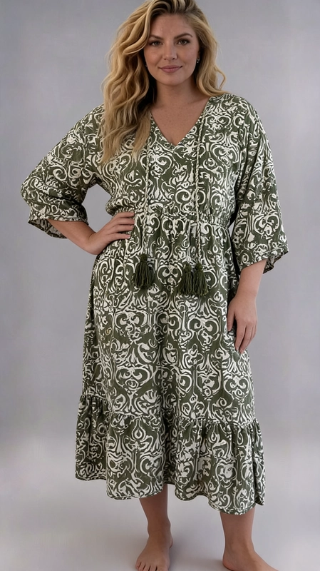 Ένα υπέροχο boho φόρεμα σε χακί πράσινο και εκρού χρώμα, με εντυπωσιακό αραβουργές μοτίβο που δημιουργεί μια αίσθηση εξωτισμού και κομψότητας. Η φαρδιά, άνετη γραμμή του το καθιστά ιδανικό για plus size σιλουέτες, προσφέροντας ελευθερία κινήσεων χωρίς να θυσιάζει το στυλ. Το βαθύ V\u002Dλαιμόκοψη με τα χαρακτηριστικά κρόσσια\u002Dφούντες σε χακί πράσινο αποτελούν το κεντρικό στοιχείο του σχεδιασμού, προσδίδοντας έναν ιδιαίτερο βοημιανό χαρακτήρα. Τα τρία τέταρτα μανίκια και το βολάν στο τελείωμα της φούστας προσθέτουν θηλυκότητα και κίνηση, ενώ η midi γραμμή το κάνει κατάλληλο για κάθε ηλικία. Ιδανικό για καλοκαιρινές εξόδους, διακοπές στην παραλία ή βόλτες στην πόλη. Μπορεί να φορεθεί με επίπεδα σανδάλια ή εσπαντρίγιες για ένα ολοκληρωμένο boho look, ή με λευκά sneakers για μια πιο casual εμφάνιση. Ένα κομμάτι που συνδυάζει άνεση και στυλ με αξεπέραστη χάρη.