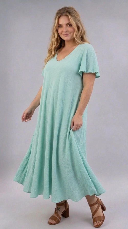 Φόρεμα πράσινο καλοκαιρινό - FRW806 | Candiashop Boutique, Ένα υπέροχο maxi φόρεμα σε παστέλ χρώμα μέντας που θα σας κάνει να ξεχωρίσετε σε κάθε περίσταση. Το μονόχρωμο σχέδιό του με ελαφρώς υφασμένη υφή προσδίδει μια εκλεπτυσμένη αίσθηση πολυτέλειας, ενώ η γραμμή Α που ακολουθεί δημιουργεί μια ρέουσα σιλουέτα που κολακεύει κάθε σώμα. Η V-λαιμόκοψη πλαισιώνει αρμονικά το ντεκολτέ, ενώ τα φαρδιά βολάν μανίκια προσθέτουν μια ρομαντική, θηλυκή πινελιά στο σύνολο. Ιδανικό για plus size γυναίκες που αναζητούν άνεση χωρίς να θυσιάζουν το στυλ. Το φόρεμα αυτό είναι τέλειο για καλοκαιρινές εκδρομές, γαμήλιες δεξιώσεις, βαπτίσεις ή ρομαντικά δείπνα. Μπορεί να συνδυαστεί με καφέ δερμάτινα πέδιλα με τακούνι, όπως στη φωτογραφία, για ένα ολοκληρωμένο, κομψό αποτέλεσμα, ή εναλλακτικά με λευκά sneakers για ένα πιο casual look. Η ελαφριά υφή του υφάσματος το καθιστά ιδανικό για τις ζεστές καλοκαιρινές μέρες, προσφέροντας άνεση και στυλ ταυτόχρονα.