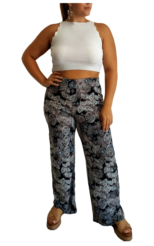 Αυτή η φαρδιά παντελόνα με εντυπωσιακό γεωμετρικό μοτίβο αποτελεί την τέλεια επιλογή για άνετο αλλά κομψό καθημερινό ντύσιμο. Σε μαύρο φόντο, διακοσμείται με περίτεχνα γεωμετρικά σχέδια σε αποχρώσεις του γκρι, γαλάζιου και λευκού, δημιουργώντας ένα μοντέρνο εθνικό στυλ που τραβάει τα βλέμματα. Η ψηλόμεση γραμμή και η φαρδιά εφαρμογή χαρίζουν άνεση και κολακεύουν κάθε σωματότυπο, ενώ οι πρακτικές τσέπες προσθέτουν λειτουργικότητα. Συνδυάστε την με το λευκό πλεκτό crop top όπως στη φωτογραφία για ένα μοντέρνο καλοκαιρινό σύνολο, ή με ένα μονόχρωμο πουκάμισο για πιο επίσημες περιστάσεις. Ιδανική για καλοκαιρινές βόλτες, παραθαλάσσιες εξορμήσεις ή χαλαρά απογευματινά ραντεβού. Το ελαφρύ, αεράτο ύφασμα προσφέρει δροσιά τις ζεστές μέρες, ενώ η άνετη εφαρμογή εξασφαλίζει ελευθερία κινήσεων. Ο συνδυασμός του εντυπωσιακού σχεδίου με την άνετη γραμμή την καθιστά ένα must\u002Dhave κομμάτι για το καλοκαιρινό σας ντουλάπα.