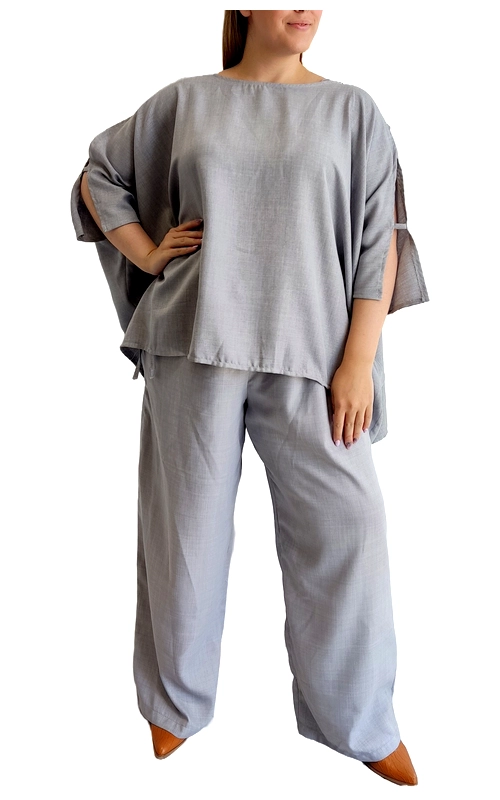 Κομψό σετ δύο τεμαχίων σε απαλό γκρι χρώμα, ιδανικό για άνετες αλλά στιλάτες εμφανίσεις. Η φαρδιά μπλούζα με την oversized σιλουέτα της προσφέρει άνεση και αέρινη αίσθηση, ενώ τα ιδιαίτερα μανίκια με τα ανοίγματα προσθέτουν μια μοντέρνα πινελιά στο σύνολο. Συνδυάζεται με την αντίστοιχη φαρδιά παντελόνα που χαρίζει ελευθερία κινήσεων και κολακεύει κάθε σωματότυπο. Το σετ είναι κατασκευασμένο από υψηλής ποιότητας λινό ύφασμα που επιτρέπει στο δέρμα να αναπνέει, καθιστώντας το ιδανική επιλογή για τις ζεστές καλοκαιρινές ημέρες ή για άνετες βραδινές εξόδους. Μπορεί να φορεθεί με μοντέρνα πέδιλα ή μποτάκια για μια πιο εκλεπτυσμένη εμφάνιση, ενώ συνδυάζεται εύκολα με διακριτικά κοσμήματα. Η απλή αλλά κομψή γραμμή του το καθιστά ιδανικό τόσο για καθημερινές εμφανίσεις όσο και για πιο επίσημες περιστάσεις, προσφέροντας άνεση χωρίς συμβιβασμούς στο στυλ.