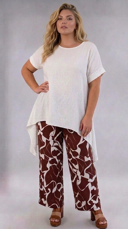 Παντελόνα γυναικεία καφέ plus size - PANT193 | Candiashop Boutique, Η παντελόνα αυτή είναι η ιδανική επιλογή για τη σύγχρονη γυναίκα που αναζητά στυλ και άνεση σε μεγάλα μεγέθη. Το εντυπωσιακό αφηρημένο μοτίβο της σε καφέ σοκολατί και κρεμ αποχρώσεις δημιουργεί μια μοναδική αισθητική που ξεχωρίζει. Η φαρδιά, palazzo γραμμή της εξασφαλίζει άψογη εφαρμογή και ελευθερία κινήσεων, ενώ το ελαφρύ, ρέον ύφασμά της την κάνει ιδιαίτερα άνετη για καθημερινή χρήση. Το γεωμετρικό, ρευστό σχέδιο με τις οργανικές φόρμες προσδίδει έναν καλλιτεχνικό χαρακτήρα, κάνοντάς την να ξεχωρίζει από τις κλασικές επιλογές. Μπορεί να φορεθεί με ένα απλό λευκό τοπ ή μπλούζα, όπως φαίνεται στη φωτογραφία, αλλά και με ένα κομψό σακάκι για πιο επίσημες εμφανίσεις. Ταιριάζει τέλεια με πέδιλα ή mules σε καφέ ή χρυσές αποχρώσεις για ένα αρμονικό σύνολο. Κατάλληλη για καλοκαιρινές εξόδους, επαγγελματικά γεύματα ή χαλαρές βόλτες, αυτή η παντελόνα αποτελεί must-have κομμάτι για κάθε plus size γκαρνταρόμπα.