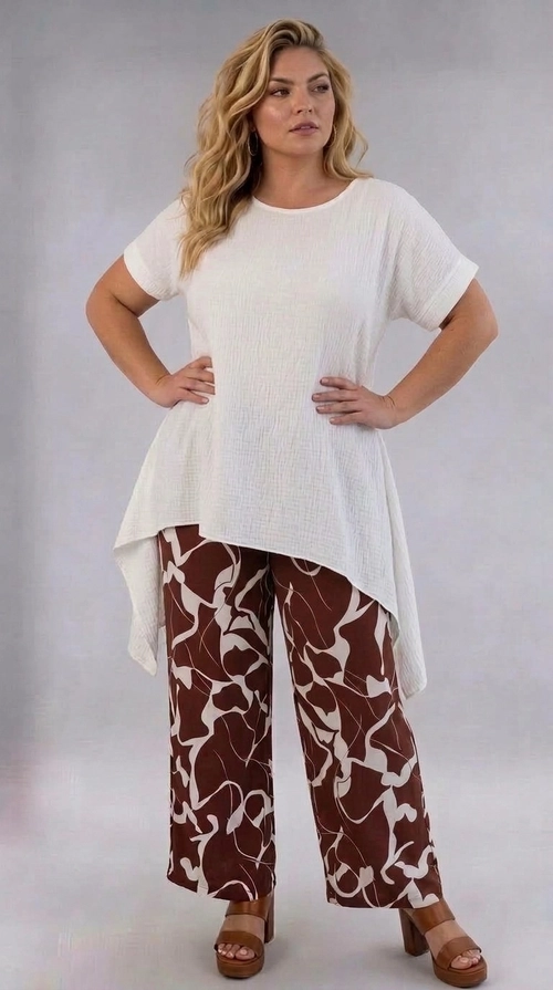Παντελόνα γυναικεία καφέ plus size - PANT193 | Candiashop Boutique, Η παντελόνα αυτή είναι η ιδανική επιλογή για τη σύγχρονη γυναίκα που αναζητά στυλ και άνεση σε μεγάλα μεγέθη. Το εντυπωσιακό αφηρημένο μοτίβο της σε καφέ σοκολατί και κρεμ αποχρώσεις δημιουργεί μια μοναδική αισθητική που ξεχωρίζει. Η φαρδιά, palazzo γραμμή της εξασφαλίζει άψογη εφαρμογή και ελευθερία κινήσεων, ενώ το ελαφρύ, ρέον ύφασμά της την κάνει ιδιαίτερα άνετη για καθημερινή χρήση. Το γεωμετρικό, ρευστό σχέδιο με τις οργανικές φόρμες προσδίδει έναν καλλιτεχνικό χαρακτήρα, κάνοντάς την να ξεχωρίζει από τις κλασικές επιλογές. Μπορεί να φορεθεί με ένα απλό λευκό τοπ ή μπλούζα, όπως φαίνεται στη φωτογραφία, αλλά και με ένα κομψό σακάκι για πιο επίσημες εμφανίσεις. Ταιριάζει τέλεια με πέδιλα ή mules σε καφέ ή χρυσές αποχρώσεις για ένα αρμονικό σύνολο. Κατάλληλη για καλοκαιρινές εξόδους, επαγγελματικά γεύματα ή χαλαρές βόλτες, αυτή η παντελόνα αποτελεί must-have κομμάτι για κάθε plus size γκαρνταρόμπα.