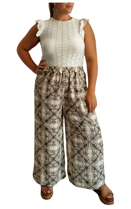 Αυτή η εντυπωσιακή γυναικεία παντελόνα συνδυάζει κομψότητα και άνεση σε ένα μοναδικό σύνολο. Το επάνω μέρος αποτελείται από ένα λευκό αμάνικο μπλουζάκι με διακριτικό κέντημα broderie anglaise και χαριτωμένα βολάν στους ώμους που προσθέτουν μια θηλυκή πινελιά. Η φαρδιά παντελόνα σε εκρού απόχρωση με καφέ γεωμετρικά μοτίβα δημιουργεί μια εντυπωσιακή αντίθεση και χαρίζει άνεση στην κίνηση. Το ψηλόμεσο σχέδιο κολακεύει τη σιλουέτα, ενώ το φαρδύ πόδι προσφέρει αέρινη αίσθηση, ιδανική για τις ζεστές καλοκαιρινές ημέρες. Φορέστε αυτό το σύνολο με πλατφόρμες ή σανδάλια για καθημερινές εξόδους, βόλτες στην παραλία ή ακόμη και για απογευματινούς καφέδες. Συνδυάστε το με ψάθινη τσάντα και διακριτικά κοσμήματα για να ολοκληρώσετε το καλοκαιρινό σας look. Η άνετη εφαρμογή και το υψηλής ποιότητας ύφασμα εξασφαλίζουν άνεση καθ\u0027 όλη τη διάρκεια της ημέρας, ενώ το διαχρονικό σχέδιο θα παραμείνει στη ντουλάπα σας για πολλές σεζόν.