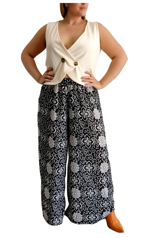 Κομψό σύνολο που συνδυάζει αέρινη άνεση με κομψότητα για καθημερινή αλλά και βραδινή εμφάνιση. Το επάνω μέρος είναι ένα μοντέρνο γιλέκο σε απαλό εκρού χρώμα με ιδιαίτερο σχεδιασμό που σταυρώνει μπροστά, διακοσμημένο με δύο κομψά καφέ κουμπιά. Συνδυάζεται αρμονικά με μια εντυπωσιακή φαρδιά παντελόνα σε μαύρο και λευκό με περίτεχνο μοτίβο που θυμίζει παραδοσιακά διακοσμητικά σχέδια. Το μοτίβο με τα λευκά λουλούδια και τους γεωμετρικούς σχηματισμούς προσθέτει κομψότητα και ιδιαίτερο χαρακτήρα. Η παντελόνα έχει άνετη γραμμή που κολακεύει κάθε σωματότυπο, ενώ το ψηλόμεσο σχέδιο αναδεικνύει τη σιλουέτα. Ιδανικό σύνολο για καλοκαιρινές βραδινές εξόδους, επαγγελματικές συναντήσεις ή περιστάσεις που απαιτούν κομψότητα με άνεση. Συνδυάστε το με ταμπά δερμάτινα αξεσουάρ και διακριτικά κοσμήματα για μια ολοκληρωμένη εμφάνιση που ξεχωρίζει.