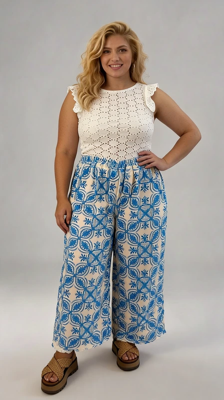 Παντελόνα γυναικεία plus size καλοκαιρινή μπλε - PANT105 | Candiashop Boutique, Αυτή η κομψή γυναικεία παντελόνα συνδυάζει άψογα το στυλ με την άνεση για τις καλοκαιρινές σας εμφανίσεις. Το πάνω μέρος αποτελείται από ένα λευκό μπλουζάκι με διάτρητο κεντητό σχέδιο και χαριτωμένα βολάν στους ώμους που προσθέτουν μια θηλυκή πινελιά. Η φαρδιά παντελόνα σε γαλάζιο και εκρού συνδυασμό διαθέτει εντυπωσιακό γεωμετρικό μοτίβο σε μεσογειακό στυλ που θυμίζει παραδοσιακά κεραμικά. Η ελαστική μέση εξασφαλίζει άνετη εφαρμογή, ενώ το φαρδύ κόψιμο προσφέρει δροσιά στις ζεστές μέρες. Ιδανική για καλοκαιρινές βόλτες, διακοπές σε νησί ή ακόμα και για περιστασιακές εξόδους. Συνδυάστε την με πλατφόρμες, όπως φαίνεται στην εικόνα, ή με επίπεδα σανδάλια για μια πιο χαλαρή εμφάνιση. Ολοκληρώστε το σύνολο με κρεμαστά σκουλαρίκια και μια ψάθινη τσάντα για την απόλυτη καλοκαιρινή εμφάνιση.