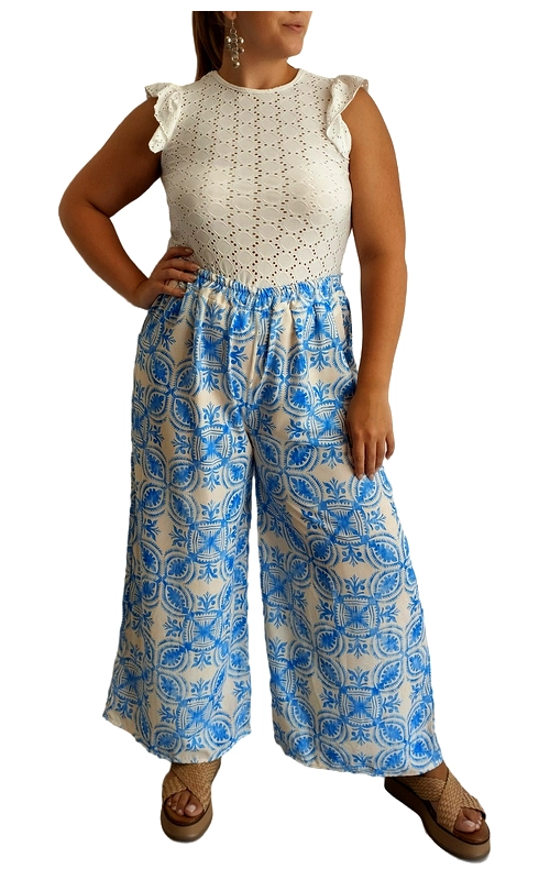 Αυτή η κομψή γυναικεία παντελόνα συνδυάζει άψογα το στυλ με την άνεση για τις καλοκαιρινές σας εμφανίσεις. Το πάνω μέρος αποτελείται από ένα λευκό μπλουζάκι με διάτρητο κεντητό σχέδιο και χαριτωμένα βολάν στους ώμους που προσθέτουν μια θηλυκή πινελιά. Η φαρδιά παντελόνα σε γαλάζιο και εκρού συνδυασμό διαθέτει εντυπωσιακό γεωμετρικό μοτίβο σε μεσογειακό στυλ που θυμίζει παραδοσιακά κεραμικά. Η ελαστική μέση εξασφαλίζει άνετη εφαρμογή, ενώ το φαρδύ κόψιμο προσφέρει δροσιά στις ζεστές μέρες. Ιδανική για καλοκαιρινές βόλτες, διακοπές σε νησί ή ακόμα και για περιστασιακές εξόδους. Συνδυάστε την με πλατφόρμες, όπως φαίνεται στην εικόνα, ή με επίπεδα σανδάλια για μια πιο χαλαρή εμφάνιση. Ολοκληρώστε το σύνολο με κρεμαστά σκουλαρίκια και μια ψάθινη τσάντα για την απόλυτη καλοκαιρινή εμφάνιση.
