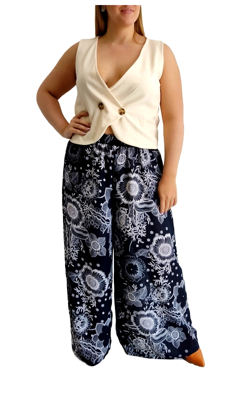 Αυτό το κομψό σύνολο αποτελείται από ένα εκρού αμάνικο τοπ με ιδιαίτερο σχεδιασμό και μια φαρδιά παντελόνα σε βαθύ ναυτικό μπλε με εντυπωσιακό φλοράλ μοτίβο. Το τοπ διαθέτει βαθύ V λαιμόκοψη και κλείνει μπροστά με δύο διακοσμητικά κουμπιά σε χρυσαφί απόχρωση, προσφέροντας μια κολακευτική γραμμή που αναδεικνύει τη σιλουέτα. Η παντελόνα έχει φαρδιά γραμμή palazzo με άνετη εφαρμογή και είναι διακοσμημένη με μεγάλα λευκά λουλούδια και φυλλώματα σε απαλές γκρι αποχρώσεις, δημιουργώντας ένα εντυπωσιακό αντίθεση με το σκούρο φόντο. Ιδανικό για καλοκαιρινές βραδινές εξόδους, αυτό το σύνολο μπορεί να φορεθεί τόσο σε καθημερινές περιστάσεις όσο και σε πιο επίσημες εκδηλώσεις. Συνδυάστε το με χρυσά αξεσουάρ και ψηλοτάκουνα πέδιλα για ένα ολοκληρωμένο εμφάνιση με στυλ. Η άνετη εφαρμογή και το ελαφρύ ύφασμα προσφέρουν άνεση καθ\u0027 όλη τη διάρκεια της ημέρας, ενώ το μοναδικό σχέδιο εγγυάται ότι θα ξεχωρίζετε με κομψότητα και θηλυκότητα.