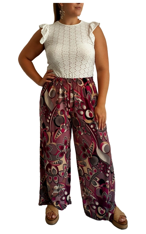Αυτό το εντυπωσιακό σύνολο συνδυάζει την κομψότητα με το στυλ, προσφέροντας μια μοναδική επιλογή για την καλοκαιρινή σας γκαρνταρόμπα. Το πάνω μέρος, σε λευκό χρώμα με διάτρητο κεντητό σχέδιο, διαθέτει χαριτωμένα βολάν στους ώμους που προσθέτουν θηλυκότητα και παιχνιδιάρικη διάθεση. Η φαρδιά παντελόνα με το εντυπωσιακό μοτίβο σε αποχρώσεις βυσσινί, μπεζ και γκρι, χαρίζει άνεση και στυλ. Τα γεωμετρικά και καλλιτεχνικά σχέδια δημιουργούν μια αίσθηση κίνησης και ζωντάνιας, ενώ η ελαστική μέση προσφέρει άνετη εφαρμογή. Ιδανικό για καλοκαιρινές βόλτες, απογευματινούς καφέδες ή ακόμα και για χαλαρές βραδινές εξόδους. Συνδυάστε το με πλατφόρμες όπως στη φωτογραφία για μια πιο casual εμφάνιση ή με ψηλοτάκουνα σανδάλια για πιο επίσημες περιστάσεις. Η αέρινη υφή της παντελόνας προσφέρει δροσιά τις ζεστές μέρες, ενώ το κομψό πάνω μέρος ισορροπεί τέλεια το έντονο σχέδιο του κάτω μέρους. Ένα πολυμορφικό σύνολο που θα αναβαθμίσει το καλοκαιρινό σας στυλ.