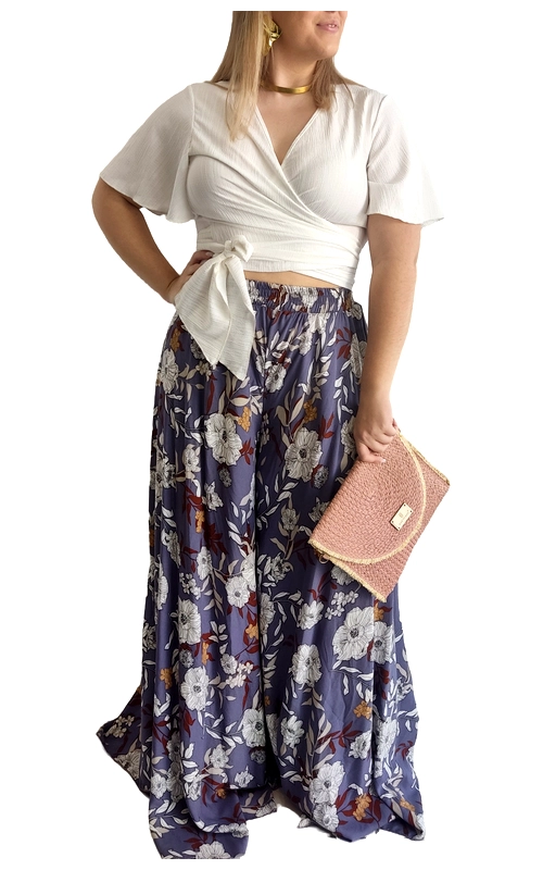Αυτή η κομψή γυναικεία παντελόνα σε μοβ\u002Dμπλε απόχρωση με φλοράλ μοτίβο αποτελεί ιδανική επιλογή για το καλοκαιρινό σας γκαρνταρόμπα. Το εντυπωσιακό σχέδιο με λευκά και καφέ λουλούδια προσδίδει θηλυκότητα και φρεσκάδα, ενώ η φαρδιά γραμμή εξασφαλίζει άνεση και αέρινη αίσθηση κατά την κίνηση. Συνδυάζεται τέλεια με το λευκό κρουαζέ τοπ με δέσιμο στη μέση και κοντά φαρδιά μανίκια, δημιουργώντας ένα αρμονικό σύνολο. Η ελαστική μέση της παντελόνας προσφέρει άνετη εφαρμογή, ενώ το ρέον ύφασμα χαρίζει δροσερή αίσθηση στις ζεστές μέρες. Ιδανική για καλοκαιρινές βόλτες, απογευματινούς καφέδες ή βραδινές εξόδους στην παραλία. Μπορεί να συνδυαστεί με πλεκτές τσάντες, όπως η ροζ τσάντα της εικόνας, και χρυσά κοσμήματα για ένα ολοκληρωμένο καλοκαιρινό look. Η παντελόνα αυτή συνδυάζει κομψότητα και άνεση, αποτελώντας ένα διαχρονικό κομμάτι που θα απογειώσει τις καλοκαιρινές σας εμφανίσεις.