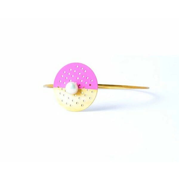 Αυτό το εντυπωσιακό statement βραχιόλι με μαργαριτάρι και ροζ χρώμα αποτελεί την τέλεια επιλογή για τη σύγχρονη γυναίκα που αγαπά τα minimal κοσμήματα με έντονη προσωπικότητα. Σχεδιασμένο από την Ελληνίδα Σχεδιάστρια Κοσμημάτων Αικατερίνη Χαλκιαδάκη, συνδυάζει την κλασική κομψότητα του μαργαριταριού με μια μοντέρνα αισθητική που ξεχωρίζει.\u000AΤο βραχιόλι διαθέτει ένα γεωμετρικό design με δύο ημικύκλια σε ροζ και χρυσαφί απόχρωση, διατρημένα με διακοσμητικές οπές που δημιουργούν ένα παιχνίδι φωτός και σκιών. Το κεντρικό μαργαριτάρι προσθέτει μια νότα πολυτέλειας, ενώ ο ποιοτικός ορείχαλκος εξασφαλίζει αντοχή και διάρκεια. Η minimal αισθητική του το καθιστά ιδανικό τόσο για καθημερινή όσο και για βραδινή εμφάνιση.\u000AΤο χειροποίητο αυτό κόσμημα αποτελεί μια εξαιρετική προσθήκη σε κάθε συλλογή, προσφέροντας ευελιξία στο styling και αποπνέοντας σύγχρονη κομψότητα.