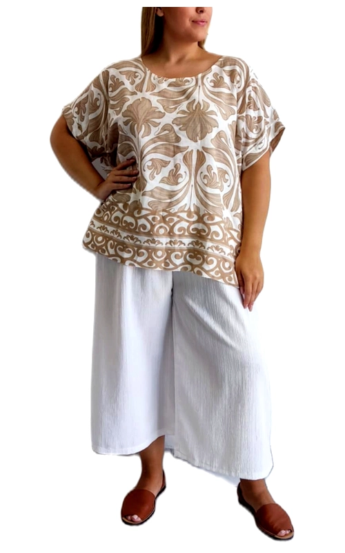 Αυτή η κομψή μπλούζα σε μπεζ και λευκό χρώμα αποτελεί την ιδανική επιλογή για το καλοκαιρινό σας γκαρνταρόμπα. Με εντυπωσιακό μπαρόκ μοτίβο σε απαλές αποχρώσεις της άμμου που διακοσμεί όλο το ύφασμα, η μπλούζα προσφέρει μια πολυτελή αίσθηση στο καθημερινό σας ντύσιμο. Ο φαρδύς σχεδιασμός με τα κοντά, αναδιπλούμενα μανίκια χαρίζει άνεση και αέρινη αίσθηση, ενώ η στρογγυλή λαιμόκοψη κολακεύει τον λαιμό. Η μπλούζα συνδυάζεται τέλεια με την λευκή φαρδιά παντελόνα που φαίνεται στην εικόνα, δημιουργώντας ένα δροσερό και κομψό σύνολο για τις ζεστές ημέρες. Είναι ιδανική για καθημερινές εμφανίσεις, βόλτες στην πόλη ή χαλαρά απογευματινά γεύματα. Το διακριτικό διακοσμητικό μοτίβο στο κάτω μέρος προσθέτει ενδιαφέρον στο σχέδιο, ενώ η χαλαρή γραμμή επιτρέπει άνετες κινήσεις και κολακεύει κάθε σωματότυπο. Φορέστε την με παντελόνες, τζιν ή φούστες για αμέτρητους συνδυασμούς που θα αναδείξουν το προσωπικό σας στυλ.