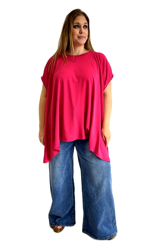 Η κοντομάνικη μπλούζα σε ζωηρό φούξια χρώμα αποτελεί την ιδανική επιλογή για κάθε γυναίκα που αγαπά τον συνδυασμό άνεσης και στυλ. Με τη ρευστή, oversized γραμμή της, χαρίζει μια αέρινη και χαλαρή εφαρμογή που κολακεύει κάθε σιλουέτα, ιδιαίτερα σε plus size μεγέθη. Το ασύμμετρο τελείωμα στο κάτω μέρος προσδίδει μοντέρνο και ιδιαίτερο χαρακτήρα, ενώ το στρογγυλό λαιμόκοψη και τα κοντά μανίκια με διακριτικό τελείωμα ολοκληρώνουν την κομψή αλλά casual αισθητική της. Το μονόχρωμο σχέδιο σε έντονο φούξια την καθιστά εύκολο να συνδυαστεί με ποικιλία ρούχων. Φορεμένη εδώ με φαρδύ τζιν παντελόνι σε μπλε ίντιγκο, δημιουργεί ένα τέλειο casual look για καθημερινές εξόδους, καφέ με φίλες ή αγορές. Μπορεί επίσης να συνδυαστεί με κολάν ή λευκό παντελόνι για ένα πιο έντονο στυλιστικό αποτέλεσμα. Το ελαφρύ ύφασμά της την κάνει ιδανική για τους ζεστούς μήνες της άνοιξης και του καλοκαιριού.