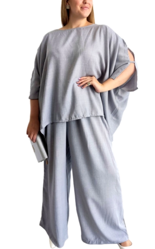 Αυτό το κομψό σετ δύο τεμαχίων σε απαλό γκρι χρώμα αποτελεί την ιδανική επιλογή για μια άνετη αλλά στυλάτη εμφάνιση. Το επάνω μέρος διαθέτει φαρδιά γραμμή με ασύμμετρο τελείωμα και χαλαρή εφαρμογή τύπου πόντσο, προσφέροντας κολακευτική κάλυψη και άνεση. Τα ανοίγματα στα μανίκια προσθέτουν μια μοντέρνα πινελιά, ενώ το λεπτό, αέρινο ύφασμα εξασφαλίζει άνεση όλη την ημέρα. Συνδυάζεται με φαρδύ παντελόνι στο ίδιο χρώμα και υλικό, δημιουργώντας ένα αρμονικό σύνολο που κολακεύει κάθε σωματότυπο. Ιδανικό για επαγγελματικές συναντήσεις, βραδινές εξόδους ή κομψές καθημερινές εμφανίσεις. Μπορεί να φορεθεί με λευκά sneakers για μια casual προσέγγιση ή με κομψά πέδιλα για πιο επίσημες περιστάσεις. Το σετ συμπληρώνεται τέλεια με διακριτικά κοσμήματα και μια μικρή τσάντα χειρός, όπως φαίνεται στην εικόνα. Η διαχρονική απόχρωση και το μινιμαλιστικό στυλ το καθιστούν βασικό κομμάτι για κάθε γυναικεία γκαρνταρόμπα.