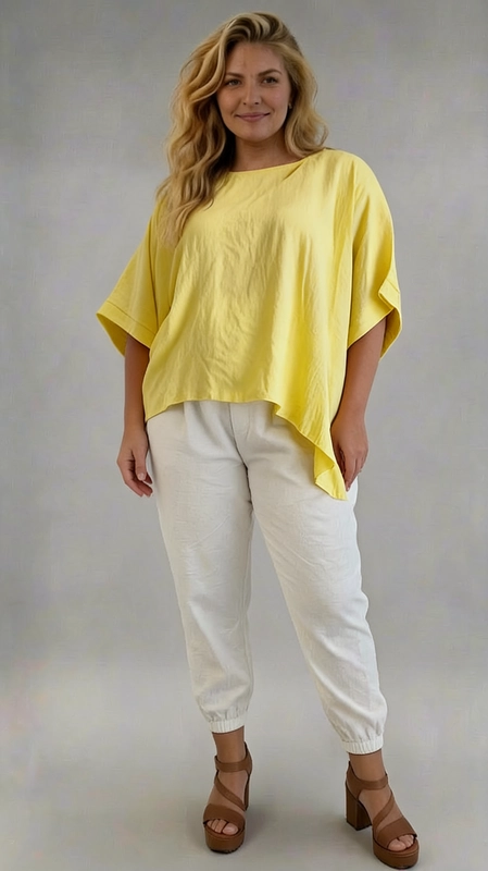 Ανακαλύψτε αυτή την εντυπωσιακή μπλούζα plus size σε ζωηρό κίτρινο χρώμα που θα φωτίσει κάθε σας εμφάνιση. Με το oversized, ασύμμετρο σχεδιασμό της και τις φαρδιές, κοντές μανσέτες, η μπλούζα αυτή προσφέρει άνεση και στυλ ταυτόχρονα, ενώ ο στρογγυλός λαιμός δίνει μια κομψή, καθαρή γραμμή. Η ελαφριά, ρέουσα ύφανση της δημιουργεί μια χαλαρή εφαρμογή που κολακεύει κάθε σιλουέτα, καθιστώντας την ιδανική για γυναίκες που αναζητούν άνεση χωρίς να θυσιάζουν την αισθητική τους. Το ασύμμετρο τελείωμα στο κάτω μέρος προσθέτει έναν μοντέρνο και δυναμικό χαρακτήρα. Μπορεί να φορεθεί με λευκό παντελόνι jogger για ένα casual καλοκαιρινό look, όπως φαίνεται στη φωτογραφία, αλλά και με τζιν ή λινό παντελόνι για πιο επίσημες περιστάσεις. Ιδανική επιλογή για καθημερινές εξόδους, καλοκαιρινές εκδρομές ή χαλαρά γεύματα, αυτή η μπλούζα είναι must\u002Dhave κομμάτι για κάθε plus size γκαρνταρόμπα.