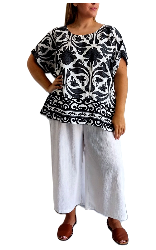 Αυτή η κομψή μπλούζα σε ασπρόμαυρο μοτίβο αποτελεί ιδανική επιλογή για την καλοκαιρινή σας γκαρνταρόμπα. Με εντυπωσιακό φλοράλ σχέδιο σε μαύρο και λευκό χρώμα, η μπλούζα διαθέτει φαρδιά γραμμή και χαλαρή εφαρμογή που κολακεύει κάθε σωματότυπο. Τα κοντά φαρδιά μανίκια προσφέρουν άνεση και δροσιά, ενώ το διακοσμητικό τελείωμα στο κάτω μέρος με γεωμετρικά μοτίβα προσθέτει μια ιδιαίτερη πινελιά στο σύνολο. Συνδυάζεται τέλεια με την απαλή λευκή παντελόνα που φαίνεται στην εικόνα, αλλά μπορεί εξίσου εύκολα να φορεθεί με τζιν, κολάν ή φούστες για διαφορετικές περιστάσεις. Ιδανική για καθημερινές εμφανίσεις, βόλτες στην πόλη ή ακόμα και για χαλαρά επαγγελματικά περιβάλλοντα. Το ελαφρύ ύφασμα και η αέρινη σιλουέτα της την καθιστούν άνετη επιλογή για τις ζεστές καλοκαιρινές μέρες, ενώ το διαχρονικό μοτίβο εξασφαλίζει ότι θα παραμείνει στη μόδα για πολλές σεζόν.