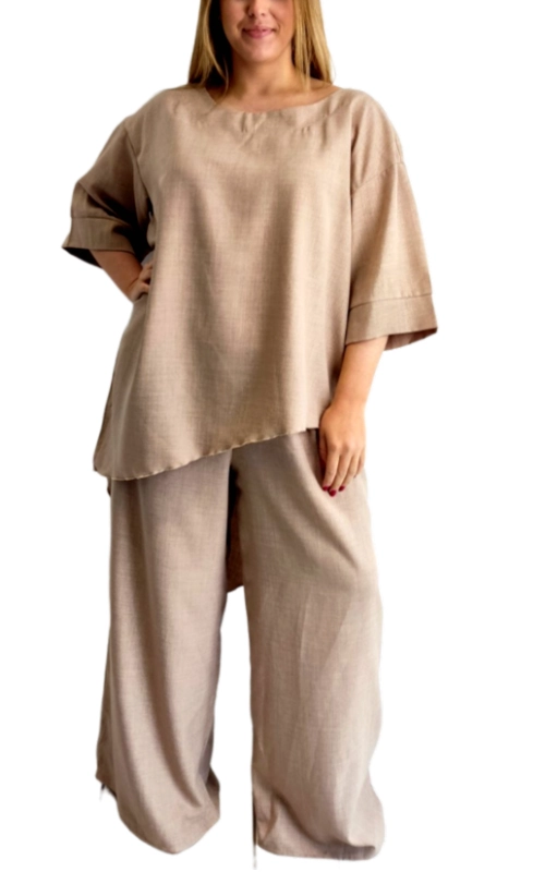 Κομψό σετ από λινό υφασμα σε απαλή μπεζ απόχρωση, ιδανικό για τις ζεστές καλοκαιρινές ημέρες. Η μπλούζα διαθέτει φαρδιά γραμμή με ασύμμετρο τελείωμα που χαρίζει μια ιδιαίτερη πινελιά στο σύνολο, ενώ τα φαρδιά μανίκια 3/4 προσφέρουν άνεση και αέρινη αίσθηση. Συνδυάζεται με την αντίστοιχη φαρδιά παντελόνα στην ίδια απόχρωση, δημιουργώντας ένα εντυπωσιακό σύνολο που κολακεύει κάθε σωματότυπο. Το φυσικό λινό υλικό επιτρέπει στο δέρμα να αναπνέει, ενώ η χαλαρή εφαρμογή προσφέρει άνετη κίνηση όλη την ημέρα. Ιδανικό για καθημερινές εμφανίσεις, βόλτες στην πόλη ή στην παραλία, αλλά και για απογευματινές εξόδους όταν συνδυαστεί με τα κατάλληλα αξεσουάρ. Μπορεί να φορεθεί με πέδιλα ή σανδάλια για μια χαλαρή εμφάνιση ή με κοσμήματα και ψηλοτάκουνα για πιο επίσημες περιστάσεις. Ένα διαχρονικό σετ που συνδυάζει κομψότητα και άνεση, ιδανικό για τη γυναίκα που αγαπά το φυσικό στυλ.