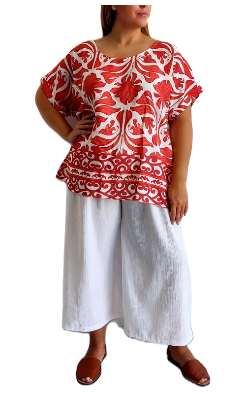 Αυτή η εντυπωσιακή μπλούζα σε κόκκινο και λευκό χρώμα αποτελεί την ιδανική επιλογή για το καλοκαιρινό σας ντύσιμο. Με φαρδιά γραμμή και χαλαρή εφαρμογή, η μπλούζα διαθέτει ένα εντυπωσιακό φλοράλ μοτίβο σε έντονο κόκκινο χρώμα πάνω σε λευκό φόντο, με διακοσμητικά μοτίβα στο κάτω μέρος που προσθέτουν μια εξωτική πινελιά. Τα κοντά, φαρδιά μανίκια προσφέρουν άνεση και δροσιά τις ζεστές ημέρες, ενώ η χαλαρή σιλουέτα κολακεύει κάθε σωματότυπο. Συνδυάζεται τέλεια με τη λευκή φαρδιά παντελόνα που φαίνεται στη φωτογραφία, δημιουργώντας ένα κομψό σύνολο για βόλτες στην πόλη, καλοκαιρινές διακοπές ή χαλαρές βραδινές εξόδους. Το ανάλαφρο ύφασμα επιτρέπει την άνετη κίνηση και εξασφαλίζει δροσερή αίσθηση ακόμα και στις πιο ζεστές μέρες. Η μπλούζα διαθέτει στρογγυλή λαιμόκοψη και μια ελαφρώς ασύμμετρη γραμμή στο τελείωμα, που προσθέτει ενδιαφέρον στο σύνολο. Ιδανική για γυναίκες που αναζητούν άνεση χωρίς να θυσιάζουν το στυλ τους.