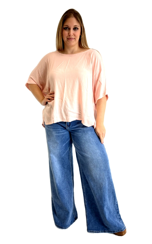 Η κοντομάνικη μπλούζα αυτή σε απαλή ροδακινί απόχρωση είναι η ιδανική επιλογή για κάθε γυναίκα που αναζητά άνεση χωρίς να θυσιάζει το στυλ της. Το oversized κόψιμό της προσφέρει χαλαρή και ελεύθερη εφαρμογή, ενώ το ελαφρύ, ρέον ύφασμα πέφτει κομψά στο σώμα δημιουργώντας μια αέρινη σιλουέτα. Ο στρογγυλός λαιμός και τα κοντά μανίκια με χαλαρό, πεσμένο ύφος προσδίδουν ένα καθημερινό και απλό αισθητικό αποτέλεσμα. Ιδιαίτερο χαρακτηριστικό της είναι το ασύμμετρο μήκος της, που είναι πιο κοντό μπροστά και λίγο πιο μακρύ πίσω, δίνοντας έτσι ένα σύγχρονο και δυναμικό look. Το μονόχρωμο, απαλό χρώμα της την καθιστά εύκολα συνδυάσιμη με πλατύ τζιν παντελόνι, κολάν ή φαρδιά παντελόνα. Κατάλληλη για καθημερινές εξόδους, ψώνια ή χαλαρές συναντήσεις με φίλους, αυτή η μπλούζα plus size συνδυάζει άψογα το στυλ με την άνεση, ανεβάζοντας το επίπεδο κάθε καθημερινής εμφάνισης.