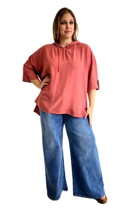 Η κοντομάνικη μπλούζα με κουκούλα σε ζεστό χρώμα σομόν\u002Dτερακότα αποτελεί την ιδανική επιλογή για κάθε γυναίκα που αναζητά στυλ και άνεση σε μεγάλα μεγέθη. Η oversized γραμμή της χαρίζει μια χαλαρή, ελεύθερη εφαρμογή που κολακεύει κάθε σιλουέτα, ενώ το ελαφρύ ύφασμά της με την υφή που θυμίζει λινό δίνει μια αίσθηση δροσιάς και εκλέπτυνσης. Διαθέτει κουκούλα με κορδόνι που προσθέτει ένα casual, σπορ άγγιγμα στο σύνολο, ενώ τα μανίκια με ρυθμιζόμενο γύρισμα επιτρέπουν να προσαρμόσεις το ύψος τους ανάλογα με τις προτιμήσεις σου. Το μήκος της πέφτει ελαφρώς πιο κάτω στις πλαϊνές ραφές, δημιουργώντας ένα κομψό asymmetric αποτέλεσμα. Μπορεί να φορεθεί με φαρδιά τζιν παντελόνια σε μπλε denim για ένα άνετο καθημερινό look, αλλά και με λευκό παντελόνι για πιο ντυμένο αποτέλεσμα. Ιδανική για καθημερινές εξόδους, αγορές ή χαλαρές βόλτες, είναι ένα must\u002Dhave κομμάτι για την γκαρνταρόμπα σου.