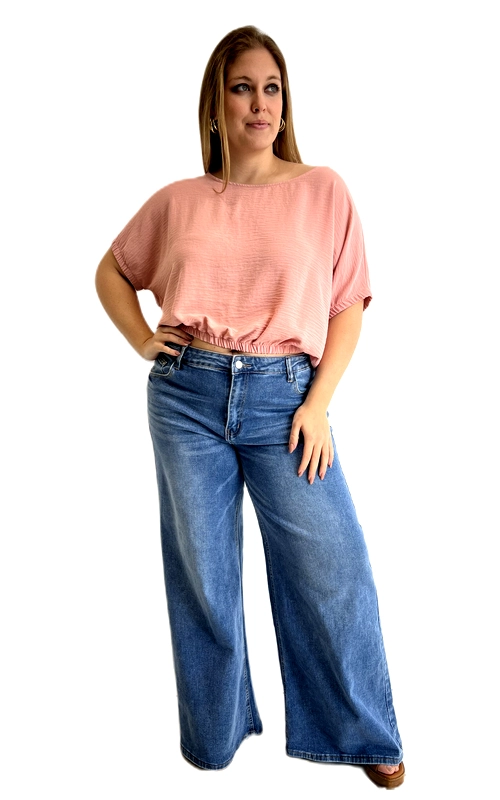 Η κοντομάνικη μπλούζα αυτή σε απαλή ροζ\u002Dσομόν απόχρωση είναι η ιδανική επιλογή για κάθε plus size γυναίκα που θέλει να συνδυάσει άνεση και στυλ. Κατασκευασμένη από ελαφρύ, υφαντό ύφασμα με λεπτή υφή, χαρίζει μια αέρινη αίσθηση καθ\u0027 όλη τη διάρκεια της ημέρας. Το oversized σχέδιό της με τα φαρδιά μανίκια ¾ τύπου νυχτερίδα δημιουργεί μια κομψή και ρευστή σιλουέτα, ενώ το ελαστικό λάστιχο στο τελείωμα της μέσης ορίζει διακριτικά το σώμα χωρίς να σφίγγει. Η στρογγυλή λαιμόκοψη προσθέτει μια γλυκιά, θηλυκή πινελιά στο σύνολο. Μπορεί να φορεθεί με φαρδύ τζιν παντελόνι, όπως στη φωτογραφία, για ένα καθημερινό και moderno look, αλλά και με λευκό ή μπεζ παντελόνι για πιο επίσημες εμφανίσεις. Ιδανική για βόλτες, καφέ με φίλες ή καλοκαιρινές εκδρομές, η μπλούζα αυτή είναι must\u002Dhave κομμάτι για κάθε γυναικεία γκαρνταρόμπα.