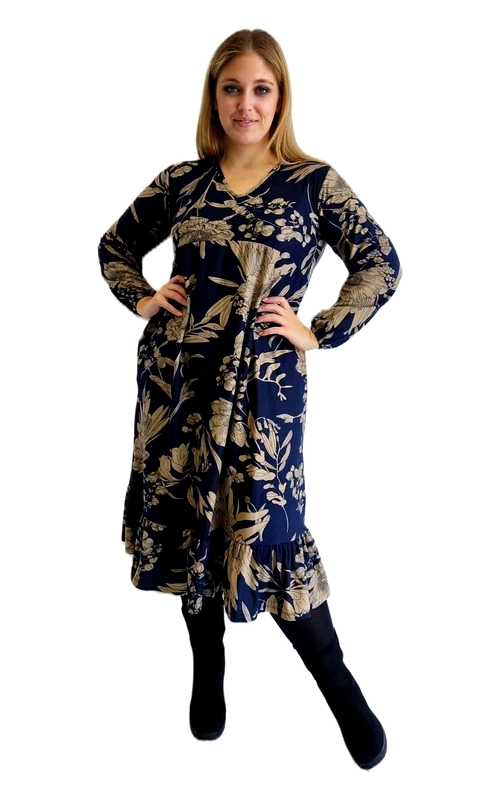 Αυτό το κομψό φόρεμα σε βαθύ blue navy με χρυσαφένιο φλοράλ μοτίβο αποτελεί την τέλεια επιλογή για τη χειμερινή σας γκαρνταρόμπα. Το μάξι μήκος του με το διακριτικό βολάν στο τελείωμα προσφέρει θηλυκότητα και άνεση, ενώ τα μακριά μανίκια παρέχουν την απαραίτητη ζεστασιά για τις κρύες μέρες. Το εντυπωσιακό σχέδιο με τα φύλλα και τα λουλούδια σε χρυσαφένιους τόνους δημιουργεί μια πολυτελή αίσθηση που τραβάει τα βλέμματα. Η γραμμή του φορέματος είναι χαλαρή αλλά κολακευτική, με V\u002Dλαιμόκοψη που αναδεικνύει το ντεκολτέ με κομψότητα. Μπορεί να φορεθεί με μαύρο καλσόν και μποτάκια για καθημερινές εμφανίσεις, ενώ με ψηλοτάκουνα παπούτσια και κατάλληλα αξεσουάρ μεταμορφώνεται σε ιδανική επιλογή για βραδινές εξόδους. Το ύφασμα είναι ελαφρύ αλλά ζεστό, επιτρέποντας άνετες κινήσεις. Ιδανικό για επαγγελματικές συναντήσεις, οικογενειακά γεύματα ή εορταστικές περιστάσεις, αυτό το φόρεμα συνδυάζει κομψότητα και πρακτικότητα σε έναν διαχρονικό σχεδιασμό.