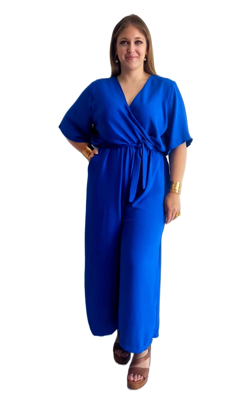 Εντυπωσιακή ολόσωμη φόρμα plus size σε ζωηρό ρουά χρώμα που αναδεικνύει κάθε σιλουέτα με στιλ και κομψότητα. Το σχέδιο wrap με βαθύ V\u002Dλαιμόκοψη προσφέρει μια θηλυκή και κολακευτική εφαρμογή, ενώ η ζώνη που δένει στη μέση τονίζει την καμπύλη και δημιουργεί ένα ψηλόμεσο αποτέλεσμα. Τα κοντά kimono μανίκια προσδίδουν έναν αέρινο και ελεύθερο χαρακτήρα, ενώ η φαρδιά παντελόνα με ίσια γραμμή εξασφαλίζει άνεση καθ\u0027 όλη τη διάρκεια της ημέρας. Το μονόχρωμο, λείο ύφασμα σε βαθύ ρουά αποπνέει πολυτέλεια και εκλέπτυνση. Ιδανική επιλογή για επαγγελματικά γεύματα, ημερήσιες εξόδους ή βραδινές εκδηλώσεις. Μπορεί να συνδυαστεί με πλατφόρμες ή γόβες σε καφέ ή χρυσές αποχρώσεις, όπως φαίνεται στην εικόνα, ενώ χρυσά αξεσουάρ όπως βραχιόλια και τσάντα ολοκληρώνουν το σύνολο με γούστο. Μια must\u002Dhave επιλογή για κάθε γυναίκα που θέλει να συνδυάσει άνεση και εμφάνιση.