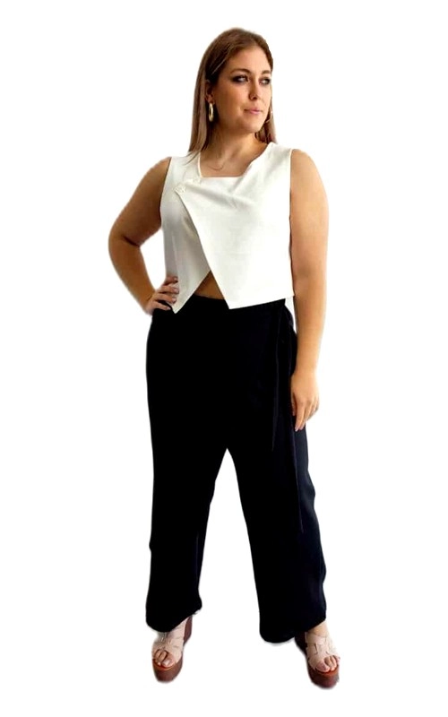 Αυτό το μοντέρνο σύνολο αποτελείται από ένα κομψό λευκό αμάνικο τοπ και ένα μαύρο φαρδύ παντελόνι, ιδανικό για την καλοκαιρινή σεζόν. Το τοπ, σε λαμπερό λευκό χρώμα, διαθέτει ασύμμετρο σχεδιασμό με επικάλυψη στο μπροστινό μέρος, που δημιουργεί ένα κομψό, γεωμετρικό αποτέλεσμα. Η γραμμή του είναι κολακευτική και σύγχρονη, προσφέροντας μια αίσθηση κομψότητας. Συνδυάζεται αρμονικά με το φαρδύ μαύρο παντελόνι, που χαρίζει άνεση και στυλ. Το παντελόνι έχει ψηλή μέση που αναδεικνύει τη σιλουέτα, ενώ η φαρδιά γραμμή του προσφέρει ελευθερία κινήσεων. Το σύνολο μπορεί να φορεθεί τόσο σε επαγγελματικές συναντήσεις όσο και σε βραδινές εξόδους, ανάλογα με τα αξεσουάρ που θα επιλέξετε. Συνδυάστε το με ψηλοτάκουνα πέδιλα για μια πιο επίσημη εμφάνιση ή με κομψά σανδάλια για πιο χαλαρές περιστάσεις. Τα διακριτικά κοσμήματα, όπως κρεμαστά σκουλαρίκια, ολοκληρώνουν ιδανικά αυτό το κομψό σύνολο.