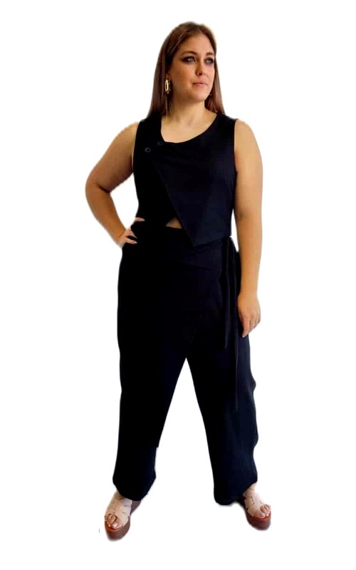 Κομψό μαύρο γυναικείο γιλέκο που συνδυάζει στυλ και άνεση για την καθημερινή σας εμφάνιση. Το αμάνικο γιλέκο με ασύμμετρο σχεδιασμό, διαθέτει ιδιαίτερο κόψιμο στην περιοχή της μέσης, που προσφέρει μια διακριτική νότα θηλυκότητας, ενώ το κουμπί στον ώμο προσθέτει μια ενδιαφέρουσα λεπτομέρεια. Συνδυάζεται με φαρδύ παντελόνι σε αντίστοιχο βαθύ μαύρο χρώμα, που χαρίζει άνεση και κομψότητα. Το σύνολο αυτό είναι ιδανικό για περιστάσεις από το πρωί μέχρι το βράδυ, καθώς μπορεί εύκολα να μεταμορφωθεί από καθημερινό σε βραδινό outfit. Φορέστε το με επίπεδα σανδάλια, όπως στην εικόνα, για μια χαλαρή εμφάνιση ή συνδυάστε το με ψηλοτάκουνα και εντυπωσιακά αξεσουάρ για βραδινές εξόδους. Η αέρινη υφή του υφάσματος εξασφαλίζει άνετη εφαρμογή για όλες τις σωματικές διαπλάσεις, αναδεικνύοντας τη σιλουέτα με κολακευτικό τρόπο. Ένα διαχρονικό κομμάτι που δεν πρέπει να λείπει από καμία γκαρνταρόμπα.