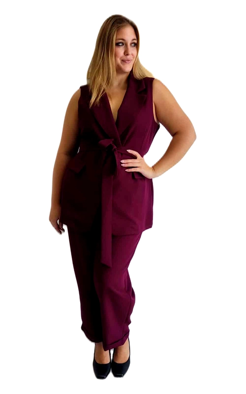 Αυτό το κομψό γυναικείο σύνολο σε πλούσιο μπορντό χρώμα αποτελείται από ένα στιλάτο αμάνικο γιλέκο και ένα ταιριαστό παντελόνι. Το γιλέκο διαθέτει κομψό πέτο και εντυπωσιακό δέσιμο στη μέση που κολακεύει τη σιλουέτα, προσφέροντας μια θηλυκή και κομψή εμφάνιση. Το παντελόνι έχει άνετη γραμμή που συνδυάζει κομψότητα και άνεση, ιδανικό για όλες τις σωματικές διαπλάσεις. Το βαθύ μπορντό χρώμα (σκούρο κεραμιδί) προσδίδει πολυτέλεια και είναι ιδανικό για όλες τις εποχές, ιδιαίτερα για το φθινόπωρο και τον χειμώνα. Μπορεί να φορεθεί σε επαγγελματικές συναντήσεις, επίσημες εκδηλώσεις ή βραδινές εξόδους. Συνδυάστε το με μαύρα ψηλοτάκουνα παπούτσια, όπως στην εικόνα, για μια ολοκληρωμένη εμφάνιση, ή προσθέστε κοσμήματα για πιο εντυπωσιακό αποτέλεσμα. Το υλικό είναι υψηλής ποιότητας, προσφέροντας άνεση και κομψότητα καθ\u0027 όλη τη διάρκεια της ημέρας. Ένα διαχρονικό κομμάτι που θα αναβαθμίσει τη γκαρνταρόμπα σας και θα σας χαρίσει αυτοπεποίθηση σε κάθε περίσταση.
