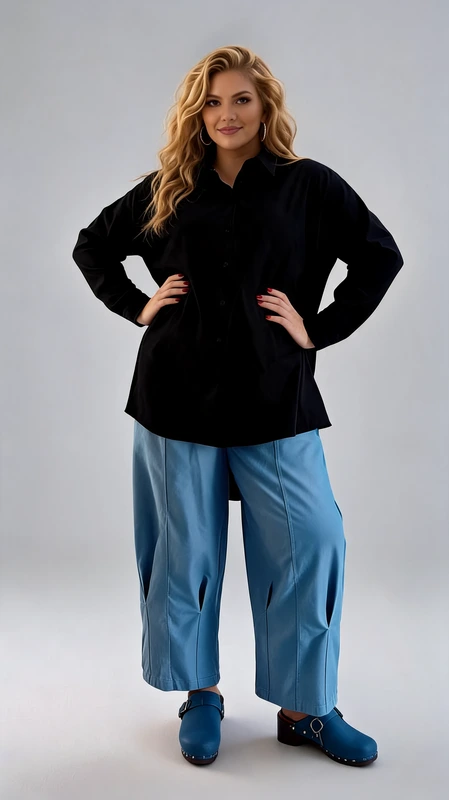 Η γυναικεία πουκαμίσα plus size σε βαθύ μαύρο χρώμα αποτελεί ένα διαχρονικό και ευέλικτο κομμάτι που κάθε γυναίκα πρέπει να έχει στη γκαρνταρόμπα της. Με το κλασικό γιακαδάκι και το κουμπάρισμα μπροστά, το σχέδιό της παραμένει απλό και κομψό, χωρίς περιττές λεπτομέρειες που να αποσπούν την προσοχή. Η oversized εφαρμογή της προσφέρει άνεση και ελευθερία κινήσεων, ενώ το μακρύ μανίκι και το επιμηκυμένο μήκος τη καθιστούν ιδανική για διάφορες περιστάσεις. Μπορεί να φορεθεί με φαρδιά παντελόνια σε γαλάζιο χρώμα, όπως φαίνεται στην εικόνα, για ένα σύγχρονο και χαλαρό look, αλλά και με στενό τζιν ή κολάν για πιο καθημερινό στυλ. Η ευέλικτη γραμμή της την κάνει κατάλληλη τόσο για επαγγελματικές όσο και για καθημερινές εξόδους. Ιδανική επιλογή για γυναίκες που αναζητούν στυλ και άνεση σε ένα μόνο κομμάτι.