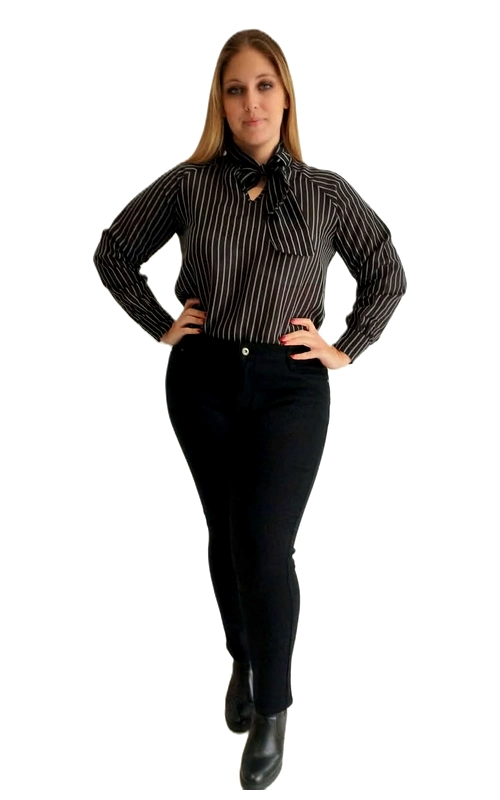 Κομψή γυναικεία πουκαμίσα plus size σε μαύρο χρώμα με λεπτές λευκές κάθετες ρίγες, που αποπνέει έναν διαχρονικό και εκλεπτυσμένο χαρακτήρα. Το εντυπωσιακό της στοιχείο είναι ο φιόγκος στο λαιμό, που προσδίδει έναν ρομαντικό και θηλυκό τόνο στο σύνολο, ενώ ταυτόχρονα δίνει μια chic, επαγγελματική αίσθηση. Οι μακριές μανσέτες μανίκια με κουμπιά ολοκληρώνουν την κλασική γραμμή του κομματιού. Η εφαρμογή της είναι ελαφρώς εφαρμοστή, τονίζοντας κολακευτικά τις καμπύλες, ενώ το ύφασμά της φαίνεται ελαφρύ και άνετο για καθημερινή χρήση. Μπορεί να φορεθεί με μαύρο ψηλόμεσο παντελόνι για ένα ολοκληρωμένο επαγγελματικό look, αλλά και με τζιν ή κλος φούστα για μια πιο casual εμφάνιση. Ιδανική για το γραφείο, επίσημα γεύματα ή βραδινές εξόδους, αυτή η πουκαμίσα αποτελεί ένα must\u002Dhave κομμάτι για κάθε γυναίκα που αγαπά τον κλασικό, διαχρονικό στυλ με μια πινελιά ρομαντισμού.