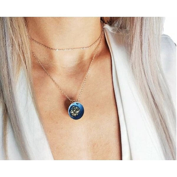 Κολιέ κοντό μπλε με πυρίτη - 10763, Ανακαλύψτε τη μαγεία ενός μοναδικού κοντού κολιέ που συνδυάζει τη φυσική ομορφιά του σιδηροπυρίτη με σύγχρονο ελληνικό design. Αυτό το εντυπωσιακό γαλάζιο κολιέ με πυρίτη, σχεδιασμένο από την Ελληνίδα Σχεδιάστρια Κοσμημάτων Αικατερίνη Χαλκιαδάκη, αποτελεί την τέλεια επιλογή για γυναίκες που αναζητούν κοσμήματα με χαρακτήρα και αυθεντικότητα.
Το χειροποίητο κολιέ διαθέτει έναν μοναδικό συνδυασμό υλικών που δημιουργεί μια εκπληκτική οπτική αντίθεση. Ο φυσικός σιδηροπυρίτης με τις μεταλλικές του αντανακλάσεις συναντά το ζεστό γαλάζιο χρώμα της ρητίνης, ενώ οι λεπτομέρειες από ορείχαλκο προσθέτουν μια vintage πινελιά. Η ορειχάλκινη αλυσίδα εξασφαλίζει άνεση και διάρκεια, καθιστώντας το ιδανικό για καθημερινή χρήση.