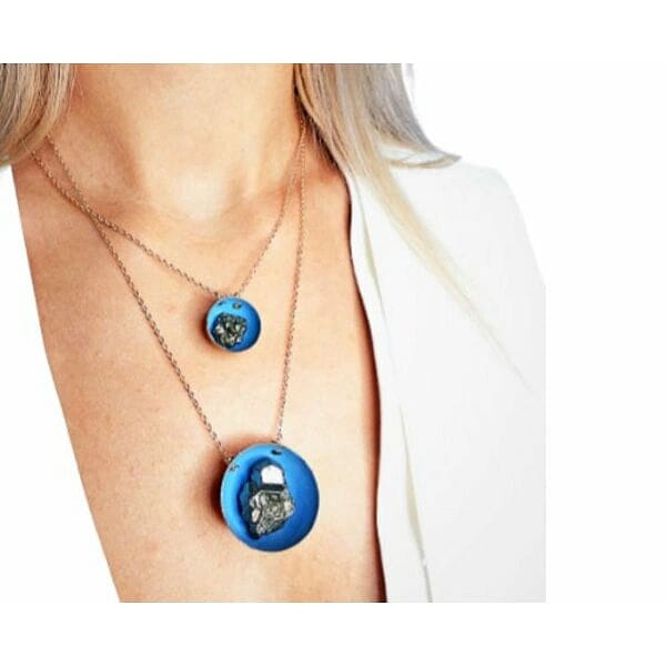 Κολιέ κοντό μπλε με πυρίτη - 10763, Ανακαλύψτε τη μαγεία ενός μοναδικού κοντού κολιέ που συνδυάζει τη φυσική ομορφιά του σιδηροπυρίτη με σύγχρονο ελληνικό design. Αυτό το εντυπωσιακό γαλάζιο κολιέ με πυρίτη, σχεδιασμένο από την Ελληνίδα Σχεδιάστρια Κοσμημάτων Αικατερίνη Χαλκιαδάκη, αποτελεί την τέλεια επιλογή για γυναίκες που αναζητούν κοσμήματα με χαρακτήρα και αυθεντικότητα.
Το χειροποίητο κολιέ διαθέτει έναν μοναδικό συνδυασμό υλικών που δημιουργεί μια εκπληκτική οπτική αντίθεση. Ο φυσικός σιδηροπυρίτης με τις μεταλλικές του αντανακλάσεις συναντά το ζεστό γαλάζιο χρώμα της ρητίνης, ενώ οι λεπτομέρειες από ορείχαλκο προσθέτουν μια vintage πινελιά. Η ορειχάλκινη αλυσίδα εξασφαλίζει άνεση και διάρκεια, καθιστώντας το ιδανικό για καθημερινή χρήση.