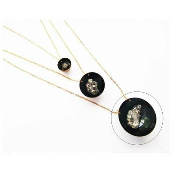 Χειροποίητο μακρύ κολιέ με πυρίτη – LARGE, Ανακαλύψτε τη μαγεία του χειροποίητου κολιέ με πυρίτη, ένα εντυπωσιακό statement κόσμημα που συνδυάζει τη φυσική ομορφιά του σιδηροπυρίτη με την κομψότητα της μαύρης πατίνας. Αυτό το μοναδικό γυναικείο κολιέ, σχεδιασμένο από την Ελληνίδα Σχεδιάστρια Κοσμημάτων Αικατερίνη Χαλκιαδάκη, αποτελεί την τέλεια επιλογή για γυναίκες που αγαπούν τα ιδιαίτερα και μοντέρνα κοσμήματα.
Ο σιδηροπυρίτης, γνωστός και ως "χρυσός των ηλιθίων", δημιουργεί εκθαμβωτικές αντανακλάσεις φωτός που προσδίδουν λάμψη και χαρακτήρα στο κολιέ. Η στρογγυλή μαύρη βάση από ορείχαλκο με την ειδική πατίνα δημιουργεί έναν εντυπωσιακό χρωματικό αντίθεση, ενώ η λεπτή χρυσαφί αλυσίδα προσθέτει κομψότητα και φινέτσα.
Αυτό το large μέγεθος κολιέ είναι ιδανικό για βραδινές εξόδους, επαγγελματικά ραντεβού ή όποτε θέλετε να ξεχωρίσετε με στυλ. Συνδυάζεται τέλεια με μαύρα, χρυσαφί ή earth tones ρούχα και μπορεί να φορεθεί μόνο του ως statement piece ή σε layering look.