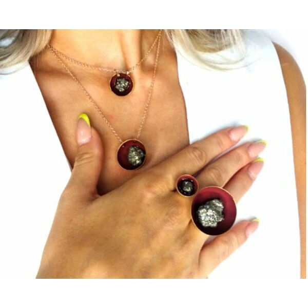 Μεγάλο εντυπωσιακό δαχτυλίδι με διπλό πυρίτη μπορντό - 10975, Ανακαλύψτε τη μαγεία του statement κοσμήματος με αυτό το μεγάλο εντυπωσιακό δαχτυλίδι με διπλό πυρίτη σε μπορντό απόχρωση. Σχεδιασμένο από την Ελληνίδα Σχεδιάστρια Κοσμημάτων Αικατερίνη Χαλκιαδάκη, αυτό το χειροποίητο γυναικείο δαχτυλίδι συνδυάζει την ελληνική τέχνη με τη σύγχρονη αισθητική.
Το δαχτυλίδι διαθέτει δύο κομψούς κύκλους διαφορετικών μεγεθών, με τον μεγαλύτερο να φέρει έναν εντυπωσιακό χρυσό σιδηροπυρίτη που λάμπει υπέροχα στο φως. Η μπορντό βάση από σμάλτο δημιουργεί έναν εκπληκτικό χρωματικό συνδυασμό που προσελκύει τα βλέμματα. Το ανθεκτικό πλαίσιο από ορείχαλκο εξασφαλίζει μακροχρόνια χρήση διατηρώντας τη λάμψη του.
Αυτό το μεγάλο δαχτυλίδι είναι ιδανικό για γυναίκες που αγαπούν τα statement κοσμήματα και θέλουν να ξεχωρίζουν. Συνδυάζεται τέλεια με βραδινά σύνολα αλλά και με casual εμφανίσεις για έναν έντονο χαρακτήρα.