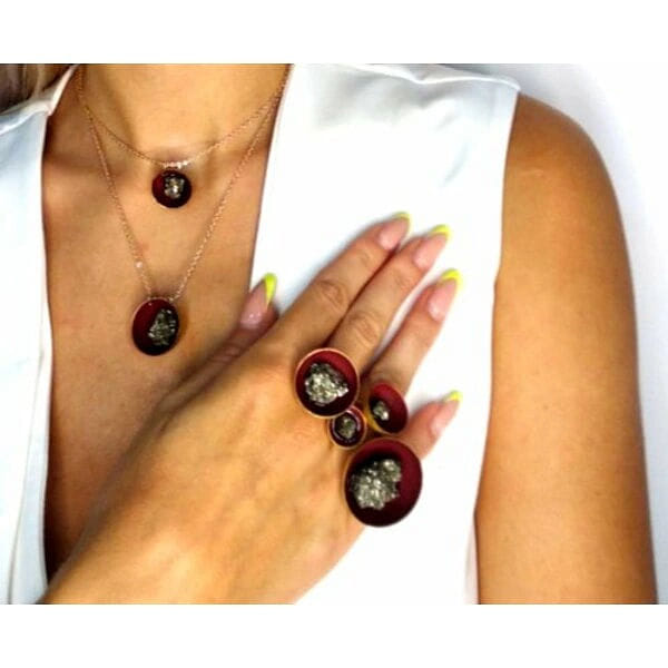 Δαχτυλίδι γυναικείο μικρό με πυρίτη μπορντό - 10986, Ανακαλύψτε τη μαγεία του χειροποίητου δαχτυλιδιού με πυρίτη σε εκπληκτική μπορντό απόχρωση που θα γίνει το αγαπημένο σας statement κόσμημα. Το μοναδικό αυτό δαχτυλίδι, σχεδιασμένο από την Ελληνίδα Σχεδιάστρια Κοσμημάτων Αικατερίνη Χαλκιαδάκη, συνδυάζει τη φυσική ομορφιά του σιδηροπυρίτη με την τέχνη του ορείχαλκου.
Το εντυπωσιακό στρογγυλό design διακοσμείται με φυσικό σιδηροπυρίτη που λαμπυρίζει με χρυσαφένιες ανταύγειες, ενώ η μπορντό επιφάνεια με τη μαύρη πατίνα δημιουργεί μια κομψή αντίθεση. Η χρυσή απόχρωση του ορείχαλκου προσθέτει πολυτέλεια και αντιγηρασιακές ιδιότητες στο κόσμημα.
Ιδανικό για γυναίκες που αγαπούν τα χειροποίητα κοσμήματα με φυσικές πέτρες, αυτό το δαχτυλίδι συνδυάζεται τέλεια με καθημερινά και βραδινά looks. Το μικρό μέγεθος το κάνει άνετο για όλη την ημέρα, ενώ η μοναδική του αισθητική το μετατρέπει σε εντυπωσιακό αξεσουάρ. Αποφύγετε την επαφή με νερό και αρώματα. Φυλάξτε σε στεγνό μέρος.