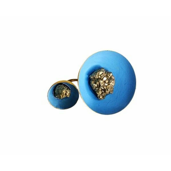 Ένα εντυπωσιακό statement δαχτυλίδι που συνδυάζει τη φυσική ομορφιά του σιδηροπυρίτη με το έντονο γαλάζιο χρώμα κιμωλίας, σχεδιασμένο από την Ελληνίδα Σχεδιάστρια Κοσμημάτων Αικατερίνη Χαλκιαδάκη. Το μεγάλο χειροποίητο δαχτυλίδι διαθέτει δύο διαφορετικές σφαίρες που δημιουργούν μια μοντέρνα και asymmetric αισθητική.\u000AΗ μεγαλύτερη σφαίρα φιλοξενεί έναν μεγάλο κρύσταλλο σιδηροπυρίτη, ενώ η μικρότερη διακοσμείται με έναν πιο μικρό κρύσταλλο, δημιουργώντας μια εντυπωσιακή σύνθεση που τραβάει τα βλέμματα. Το χρώμα της κιμωλίας σε γαλάζια απόχρωση προσδίδει μια μοναδική vintage αύρα, ενώ ο ορείχαλκος εξασφαλίζει ανθεκτικότητα και διάρκεια.\u000AΑυτό το χειροποίητο γυναικείο δαχτυλίδι είναι ιδανικό για όσες αγαπούν τα μεγάλα κοσμήματα που κάνουν statement. Συνδυάζεται τέλεια με casual και bohemian looks, προσδίδοντας έναν εκλεκτικό χαρακτήρα σε κάθε εμφάνιση.