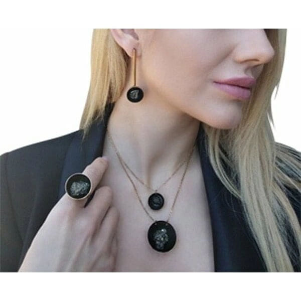 Χειροποίητο γυναικείο δαχτυλίδι με πυρίτη - 3001, Ανακαλύψτε τη μαγεία του χειροποίητου γυναικείου δαχτυλιδιού με πυρίτη, ένα μοναδικό κόσμημα που συνδυάζει τη δύναμη των φυσικών πετρών με τη σύγχρονη αισθητική. Σχεδιασμένο από την Ελληνίδα Σχεδιάστρια Κοσμημάτων Αικατερίνη Χαλκιαδάκη, αυτό το εντυπωσιακό δαχτυλίδι αποτελεί την τέλεια επιλογή για γυναίκες που αναζητούν statement κοσμήματα με χαρακτήρα.
Η ωοειδής σιλουέτα του δαχτυλιδιού περιβάλλεται από χρυσαφί ορείχαλκο, ενώ στο κέντρο κυριαρχεί η μαύρη πατίνα που φιλοξενεί έναν φυσικό σιδηροπυρίτη. Ο πυρίτης, γνωστός και ως "χρυσός του τρελού", προσφέρει μεταλλικές ανταύγειες που δημιουργούν έναν μαγευτικό οπτικό διάλογο με το μαύρο φόντο.
Το μεγάλο μέγεθος του δαχτυλιδιού το καθιστά ιδανικό για όσες προτιμούν εντυπωσιακά κοσμήματα που ξεχωρίζουν. Η χειροποίητη κατασκευή εγγυάται την μοναδικότητα κάθε κομματιού, καθιστώντας το ένα πραγματικό έργο τέχνης.