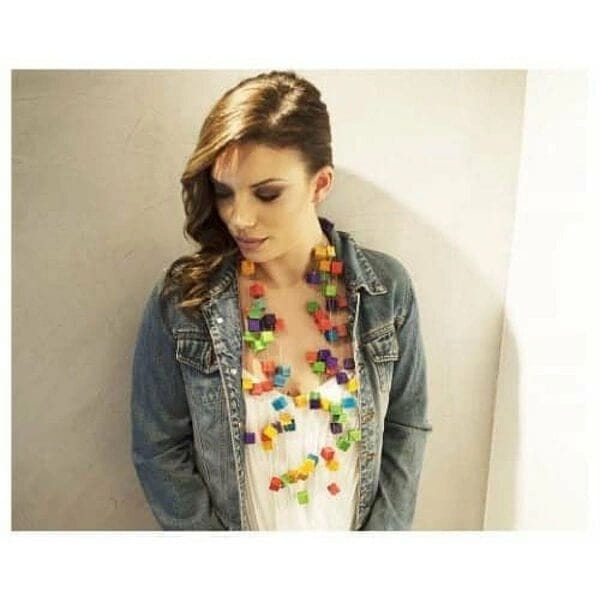 Μεγάλο εντυπωσιακό γυναικείο statement κολιέ με ξύλο και χρώμα - 2995, Ανακαλύψτε ένα μοναδικό statement κολιέ που συνδυάζει δημιουργικότητα με πρωτότυπο σχεδιασμό, εμπνευσμένο από τον εμβληματικό Κύβο του Rubik. Αυτό το εντυπωσιακό γυναικείο κολιέ με ξύλινους κύβους, σχεδιασμένο από την Ελληνίδα Σχεδιάστρια Κοσμημάτων Αικατερίνη Χαλκιαδάκη, αποτελεί την ιδανική επιλογή για γυναίκες που επιθυμούν να ξεχωρίσουν με στυλ και προσωπικότητα.
Κάθε χρωματιστός ξύλινος κύβος έχει διαμορφωθεί με ιδιαίτερη προσοχή, δημιουργώντας έναν καλειδοσκόπιο χρωμάτων που περιλαμβάνει ζωηρά κόκκινα, πράσινα, μπλε, πορτοκαλί, κίτρινα και μοβ αποχρώσεις. Η σύνθεση των πολύχρωμων κύβων σε διαφορετικά επίπεδα του κολιέ δημιουργεί ένα δυναμικό και playful aesthetic που προσελκύει τα βλέμματα.
Το χειροποίητο κολιέ φέρει διπλό κορδόνι που επιτρέπει άνετη προσαρμογή και σταθερότητα κατά τη φορεσιά. Είναι ιδανικό για casual εμφανίσεις, creative επαγγελματικά περιβάλλοντα ή ως conversation starter σε κοινωνικές συναντήσεις.