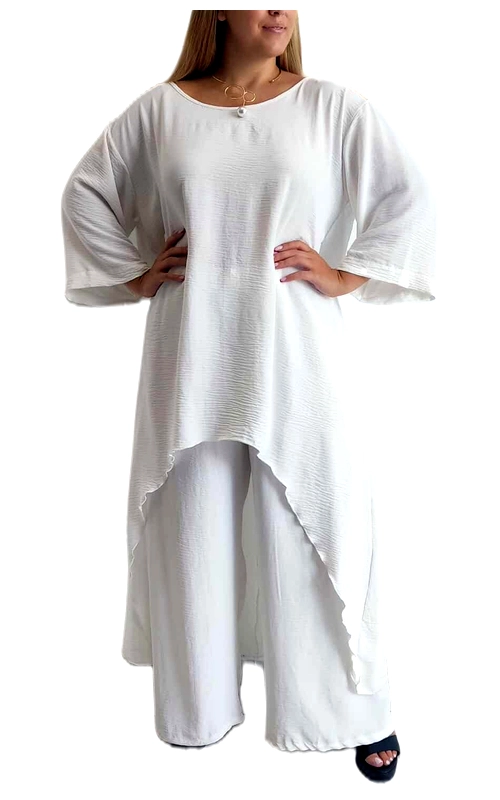 Αυτό το κομψό σετ σε λευκό χρώμα αποτελείται από μια φαρδιά μπλούζα με ασύμμετρο τελείωμα και ένα άνετο παντελόνι. Η μπλούζα διαθέτει εντυπωσιακά φαρδιά μανίκια τύπου νυχτερίδας και χαλαρή γραμμή στο στήθος που χαρίζει άνεση και στυλ. Το ύφασμα έχει διακριτική υφή με λεπτές ραβδώσεις που προσθέτουν ενδιαφέρον στο λευκό χρώμα, ενώ το μήκος της είναι μεγαλύτερο στο πίσω μέρος, δημιουργώντας μια κολακευτική σιλουέτα. Το παντελόνι έχει φαρδιά γραμμή που συμπληρώνει τέλεια την μπλούζα, προσφέροντας άνεση και κομψότητα. Το σετ είναι ιδανικό για καλοκαιρινές εξόδους, παραθαλάσσιες διακοπές ή ακόμα και για πιο επίσημες περιστάσεις όταν συνδυαστεί με τα κατάλληλα αξεσουάρ. Μπορείτε να το φορέσετε με χρυσά κοσμήματα, όπως το διακριτικό κολιέ που φαίνεται στη φωτογραφία, και με πέδιλα ή σανδάλια για μια ολοκληρωμένη εμφάνιση. Το υλικό είναι ελαφρύ και αεράτο, ιδανικό για τις ζεστές μέρες, ενώ η χαλαρή εφαρμογή κολακεύει κάθε σωματότυπο.