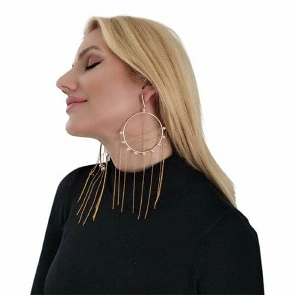 Μεγάλα εντυπωσιακά σκουλαρίκια κρεμαστά με πέρλες - 2970, Ανακαλύψτε τη μαγεία των μεγάλων εντυπωσιακών σκουλαρικιών κρεμαστών με πέρλες που θα μεταμορφώσουν κάθε σας εμφάνιση. Αυτά τα μοναδικά χειροποίητα σκουλαρίκια "Ονειροπαγίδα", σχεδιασμένα από την Ελληνίδα Σχεδιάστρια Κοσμημάτων Αικατερίνη Χαλκιαδάκη, συνδυάζουν τη σύγχρονη αισθητική με την παραδοσιακή ελληνική τεχνοτροπία.
Κατασκευασμένα από υψηλής ποιότητας ορείχαλκο με χρυσή απόχρωση, τα σκουλαρίκια διαθέτουν γεωμετρικό σχέδιο κύκλων που στολίζονται με φυσικές πέρλες. Οι κρεμαστές αλυσίδες δημιουργούν μια κομψή κίνηση που προσελκύει τα βλέμματα, ενώ το statement design τους τα καθιστά ιδανικά για ιδιαίτερες στιγμές.
Τα μακριά σκουλαρίκια συνδυάζονται τέλεια με βραδινά σύνολα, νυφικές εμφανίσεις ή boho chic looks, προσφέροντας μια πινελιά πολυτέλειας και μυστηρίου. Η εργονομική τους κατασκευή εξασφαλίζει άνεση όλη μέρα.