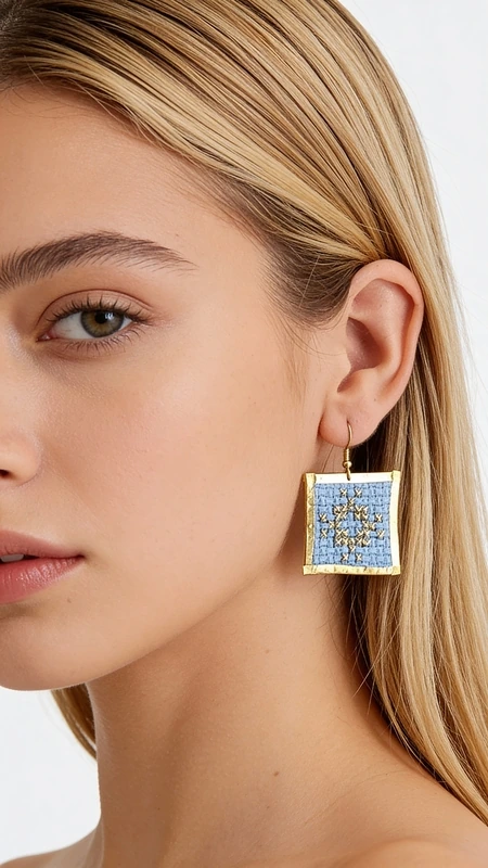 Κεντητά σκουλαρίκια statement με γεωμετρικά σχέδια από χρυσοκλωστή σε γαλάζιο - SKOUL-4700, Τα statement σκουλαρίκια με κεντητά γεωμετρικά σχέδια σε γαλάζιο χρώμα θα γίνουν το αγαπημένο σας αξεσουάρ για κάθε ιδιαίτερη περίσταση. Σχεδιασμένα από την Ελληνίδα Σχεδιάστρια Κοσμημάτων Αικατερίνη Χαλκιαδάκη, αυτά τα εντυπωσιακά χειροποίητα σκουλαρίκια συνδυάζουν την παραδοσιακή τέχνη του κεντήματος με σύγχρονο design.
Η χρυσοκλωστή σε απαλό γαλάζιο χρώμα δημιουργεί ένα μοναδικό γεωμετρικό μοτίβο που προσθέτει κομψότητα και στυλ σε κάθε εμφάνιση. Τα κεντητά σκουλαρίκια έχουν τετράγωνο σχήμα και μεσαίο μέγεθος, ιδανικό για να κάνουν statement χωρίς να είναι υπερβολικά βαριά. Η λεπτομερής χειροτεχνία και το folklore design τους κάνουν ιδιαίτερα για βραδινές εξόδους, ειδικές εκδηλώσεις ή ακόμα και για γαμήλιες εμφανίσεις. Συντηρήστε τα σκουλαρίκια σας αποθηκεύοντάς τα σε στεγνό μέρος και αποφεύγοντας την επαφή με νερό ή χημικά προϊόντα για να διατηρήσουν το χρώμα τους.
Υλικό: Ορείχαλκος, Ύφασμα