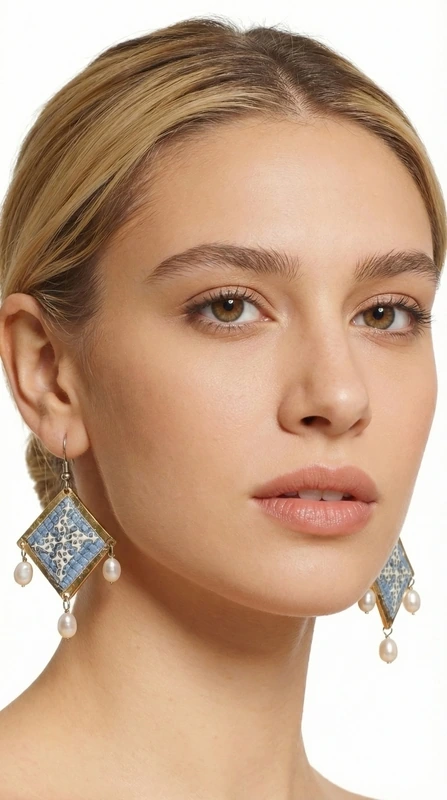 Τα statement κεντητά σκουλαρίκια σε γαλάζιο χρώμα με γεωμετρικά σχέδια από χρυσοκλωστή αποτελούν το ιδανικό χειροποίητο κόσμημα για να αναδείξετε τη μοναδικότητά σας. Αυτά τα εντυπωσιακά κρεμαστά σκουλαρίκια, σχεδιασμένα από την Ελληνίδα Σχεδιάστρια Κοσμημάτων Αικατερίνη Χαλκιαδάκη, συνδυάζουν την παραδοσιακή τέχνη του κεντήματος με μοντέρνα αισθητική.\u000AΗ γαλάζια απόχρωση σε συνδυασμό με τη χρυσοκλωστή δημιουργεί μια εκλεπτυσμένη αντίθεση που προσελκύει τα βλέμματα. Τα γεωμετρικά σχέδια προσδίδουν σύγχρονο χαρακτήρα, ενώ οι λεπτές πέρλες που κρέμονται από τη βάση των σκουλαρικιών προσθέτουν κίνηση και θηλυκότητα. Το folklore design τους τα καθιστά ιδανικά για ιδιαίτερες στιγμές, από νυφικές εμφανίσεις έως κοκτέιλ παρτυ. Ιδανικά σκουλαρίκαι για γάμους, βαπτίσεις και ιδιαίτερες εκδηλώσεις. Συντηρείστε τα με προσοχή, αποφεύγοντας την επαφή με νερό και αρώματα για μεγαλύτερη διάρκεια ζωής.\u000AΥλικό: Ορείχαλκος, Ύφασμα \u000AΠέτρα: Πέρλα