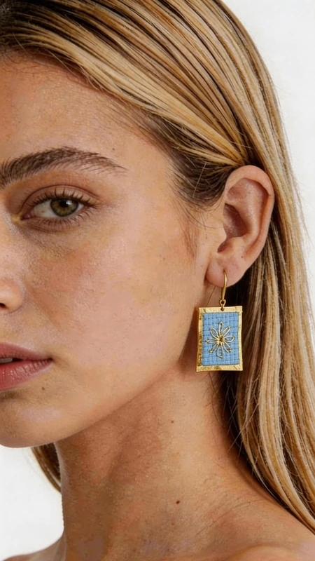 Κεντητά σκουλαρίκια statement με γεωμετρικά σχέδια από χρυσοκλωστή σε γαλάζιο - SKOUL-4706 | Candiashop Boutique, Τα statement κεντητά σκουλαρίκια με γεωμετρικά σχέδια από χρυσοκλωστή σε γαλάζιο αποτελούν έναν μοναδικό συνδυασμό παραδοσιακής τέχνης και μοντέρνου σχεδιασμού. Σχεδιασμένα από την Ελληνίδα Σχεδιάστρια Κοσμημάτων Αικατερίνη Χαλκιαδάκη, αυτά τα εντυπωσιακά χειροποίητα σκουλαρίκια αναδεικνύουν την κομψότητα κάθε look με στιλ και χαρακτήρα. Η λεπτή κεντητική τεχνική με χρυσοκλωστή δημιουργεί ένα υπέροχο αποτέλεσμα που λαμπυρίζει διακριτικά, ενώ το γαλάζιο χρώμα προσφέρει μια φρεσκάδα που ταιριάζει τέλεια με θερινά και καλοκαιρινά outfit. Τα γεωμετρικά σχέδια προσδίδουν μοντέρνα αισθητική, κάνοντας τα εντυπωσιακά σκουλαρίκια ιδανική επιλογή για κάθε περίσταση. Τα χειροποίητα κεντητά σκουλαρίκια είναι τέλεια για γάμους, βαφτίσια, καλοκαιρινά πάρτι και κάθε ειδική στιγμή όπου θέλετε να ξεχωρίσετε. Συνδυάστε τα με λευκό ή μπλε ρούχα για να αναδείξετε το γαλάζιο τους χρώμα. Υλικό: Ορείχαλκος, Ύφασμα Φροντίστε τα σκουλαρίκια σας αποθηκεύοντάς τα σε στεγνό μέρος, μακριά από υγρασία και άμεση ηλιακή ακτινοβολία για να διατηρήσουν τη λάμψη τους.