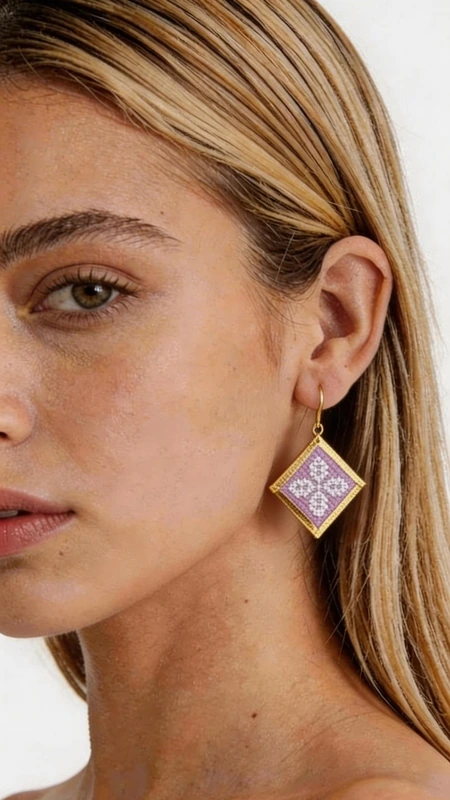 Κεντητά σκουλαρίκια statement με γεωμετρικά σχέδια από χρυσοκλωστή σε λιλά - SKOUL-4709 | Candiashop Boutique, Τα statement κεντητά σκουλαρίκια σε λιλά απόχρωση με γεωμετρικά σχέδια από χρυσοκλωστή είναι η τέλεια επιλογή για να προσθέσετε μια πινελιά κομψότητας και πρωτοτυπίας στην εμφάνισή σας. Σχεδιασμένα από την Ελληνίδα Σχεδιάστρια Κοσμημάτων Αικατερίνη Χαλκιαδάκη, αυτά τα χειροποίητα σκουλαρίκια συνδυάζουν την παραδοσιακή τεχνική του κεντήματος με σύγχρονο design. Η τετράγωνη γεωμετρική φόρμα τους διακοσμείται με περίτεχνα κεντημένα μοτίβα σε μαλακή λιλά απόχρωση, ενώ το χρυσό περίγραμμα προσδίδει μια πολυτελή πινελιά. Το folklore design με τα λεπτομερή γεωμετρικά σχέδια δημιουργεί ένα μοναδικό κόσμημα που ξεχωρίζει και συμπληρώνει τόσο casual όσο και επίσημα looks. Ιδανικά για γυναίκες που αγαπούν τα εντυπωσιακά αξεσουάρ, αυτά τα σκουλαρίκια είναι τέλεια για ειδικές περιστάσεις, γάμους ή για να προσθέσουν χρώμα στην καθημερινότητά σας. Υλικό: Ορείχαλκος, Ύφασμα Για τη φροντίδα τους, φυλάσσετε τα σκουλαρίκια σε στεγνό μέρος και αποφεύγετε την επαφή με νερό και χημικά.